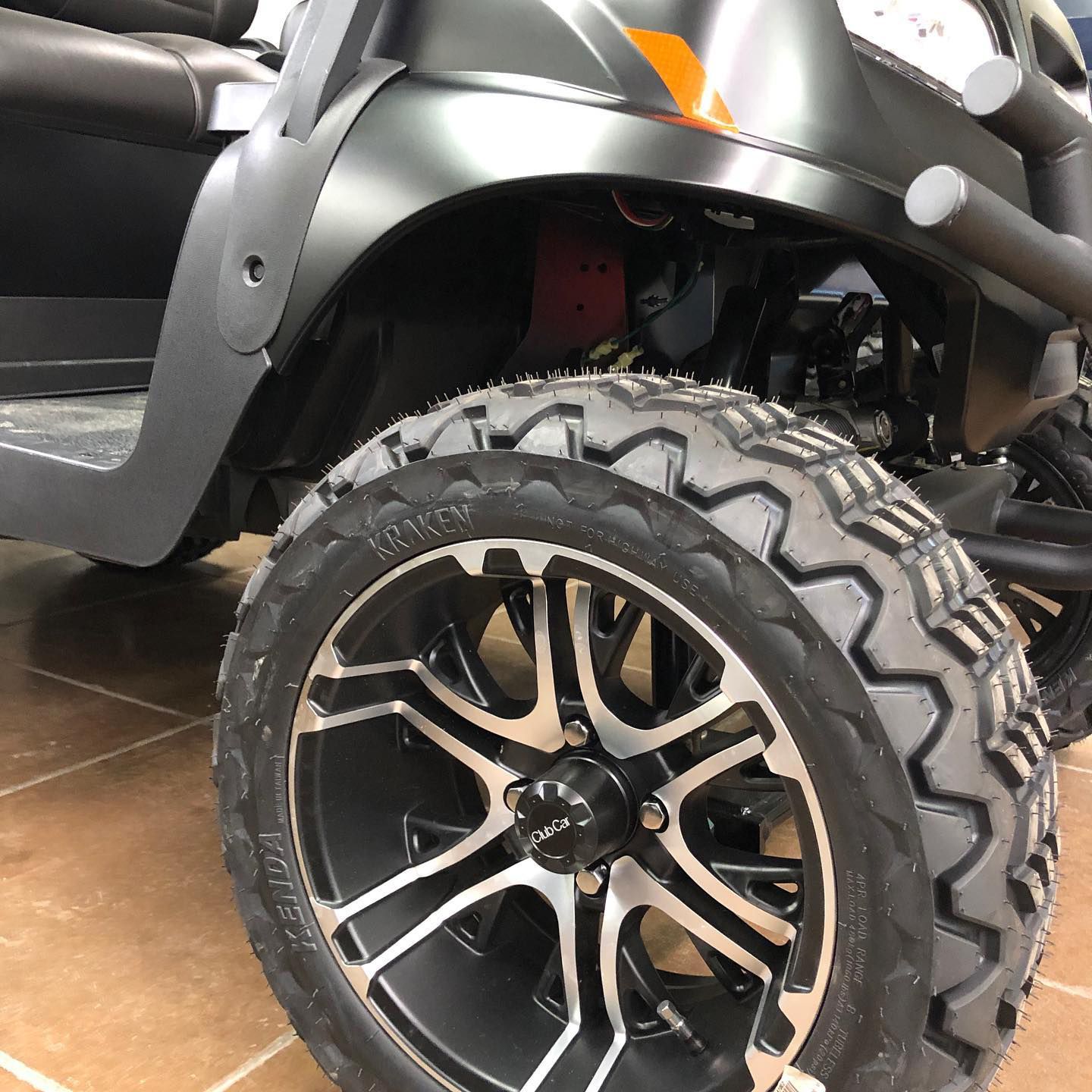A golf cart is parked on a tiled floor.
