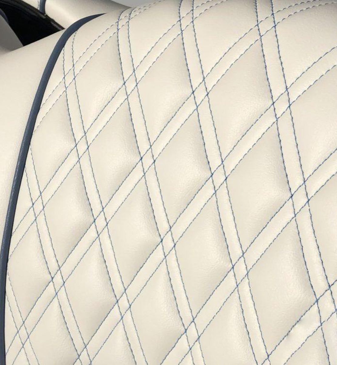 A close up of a white leather seat with blue stitching