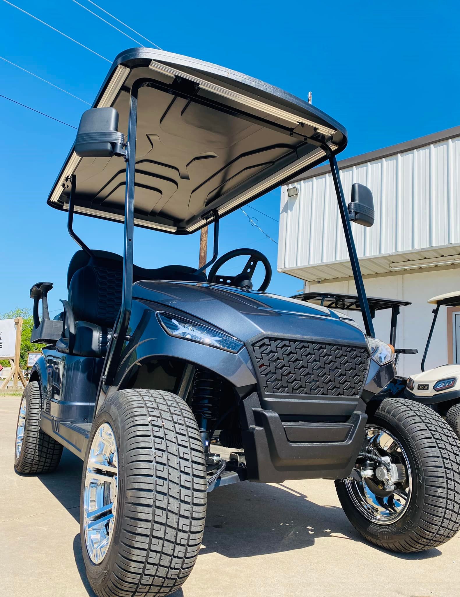 A black golf cart is parked in front of a building.