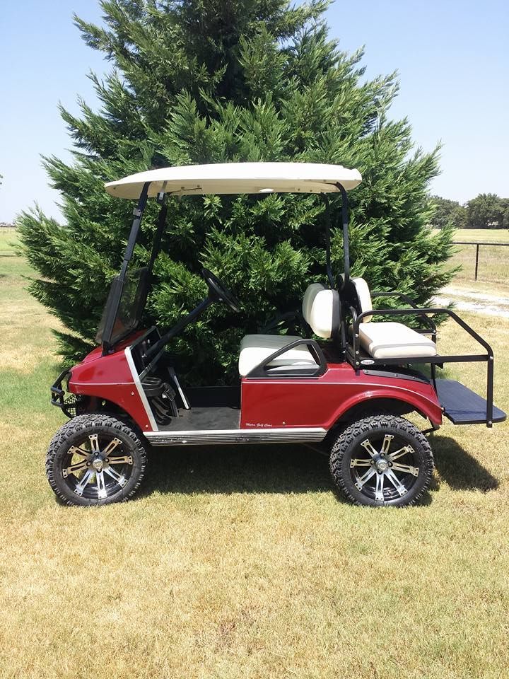 A red golf cart is parked in front of a tree