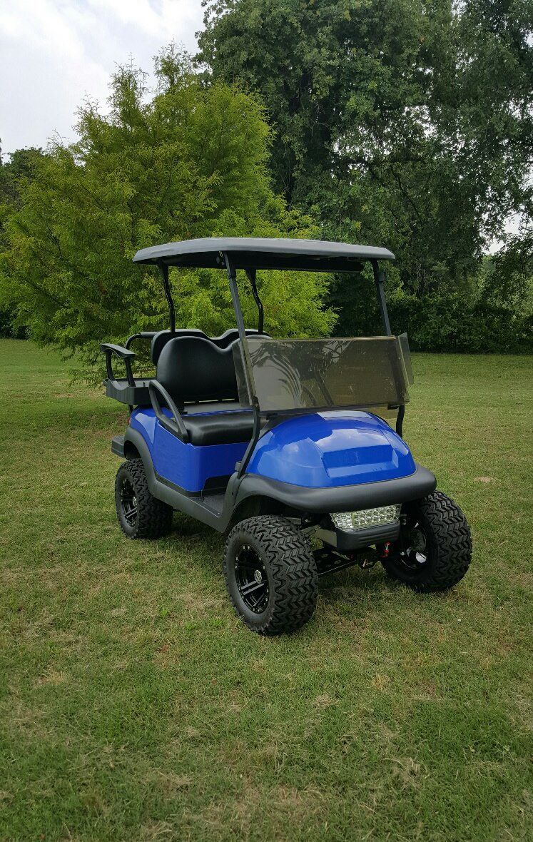 A blue golf cart is parked in a grassy field.