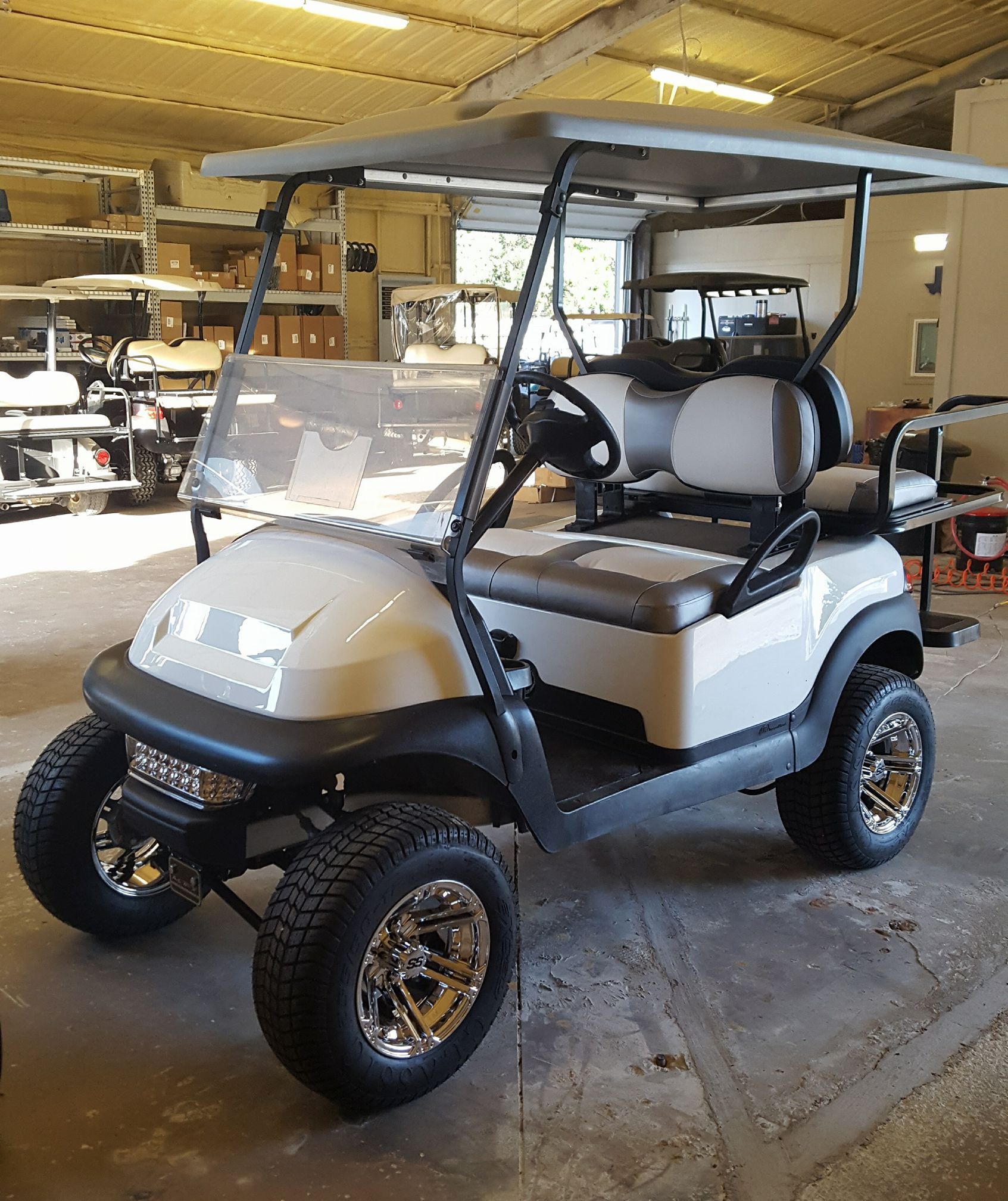 A white golf cart is parked in a garage.