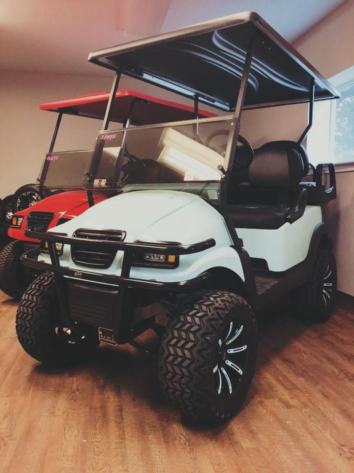A white golf cart is parked next to a red golf cart.