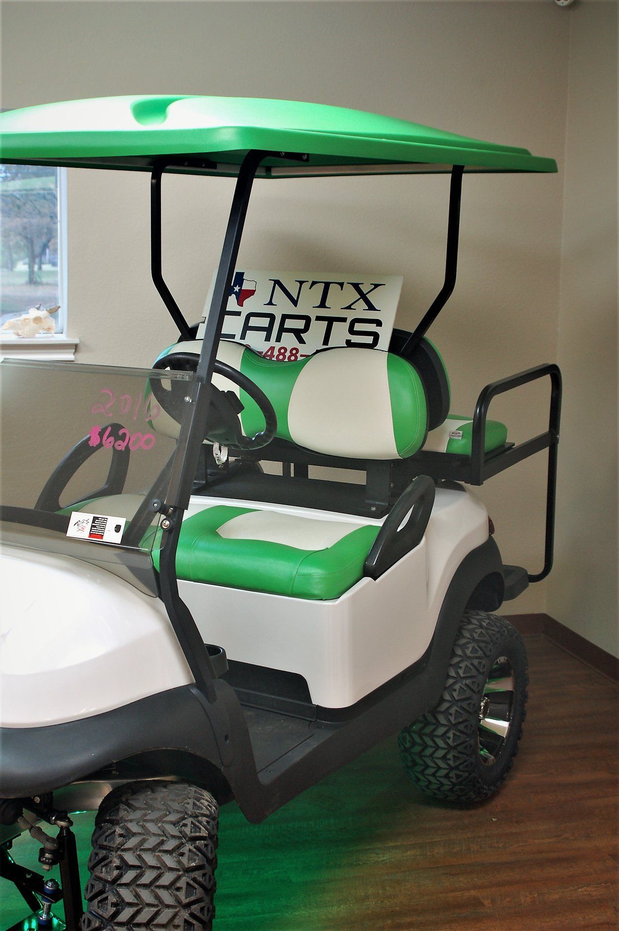 A green and white golf cart with a sign that says ntx carts