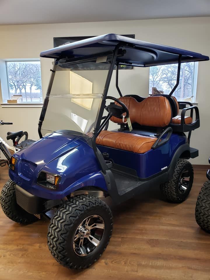 A blue golf cart with brown seats is parked in a room.
