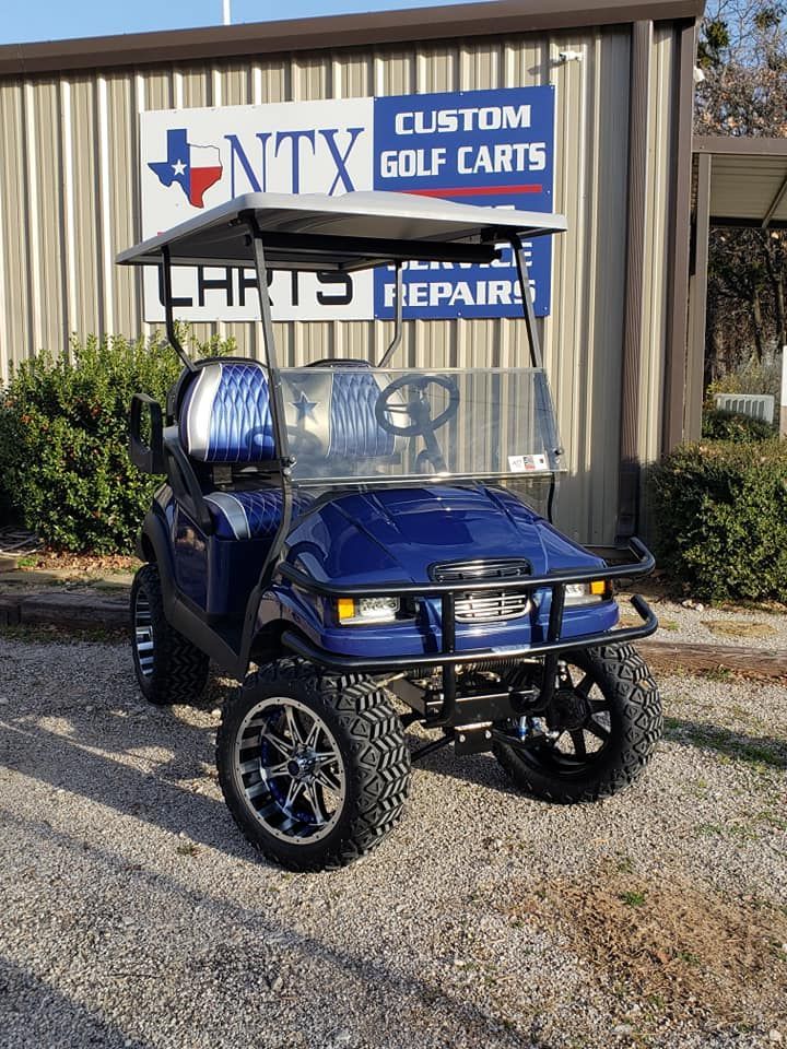 A blue golf cart is parked in front of a building.