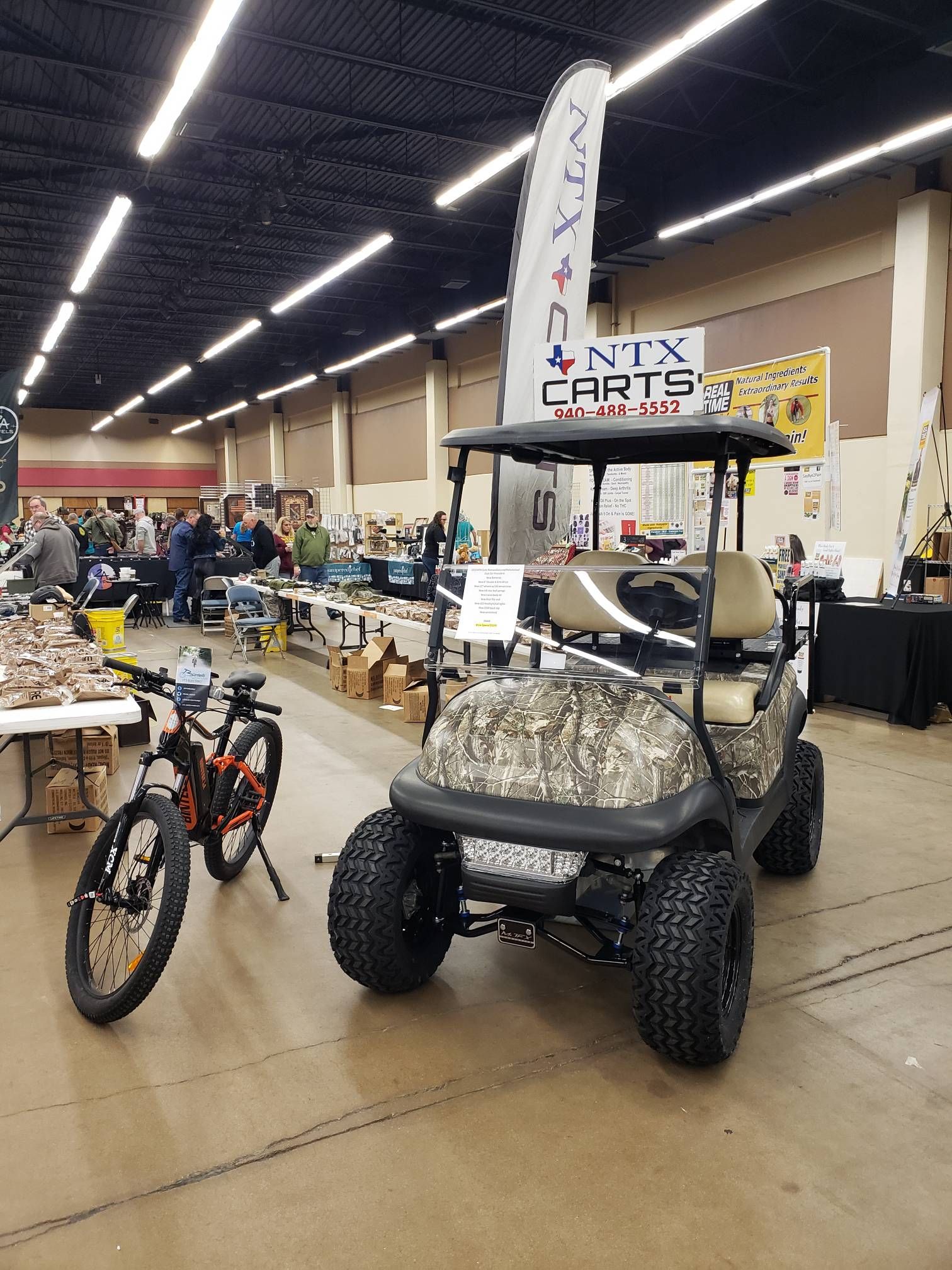 A golf cart is parked in a room next to a bicycle.