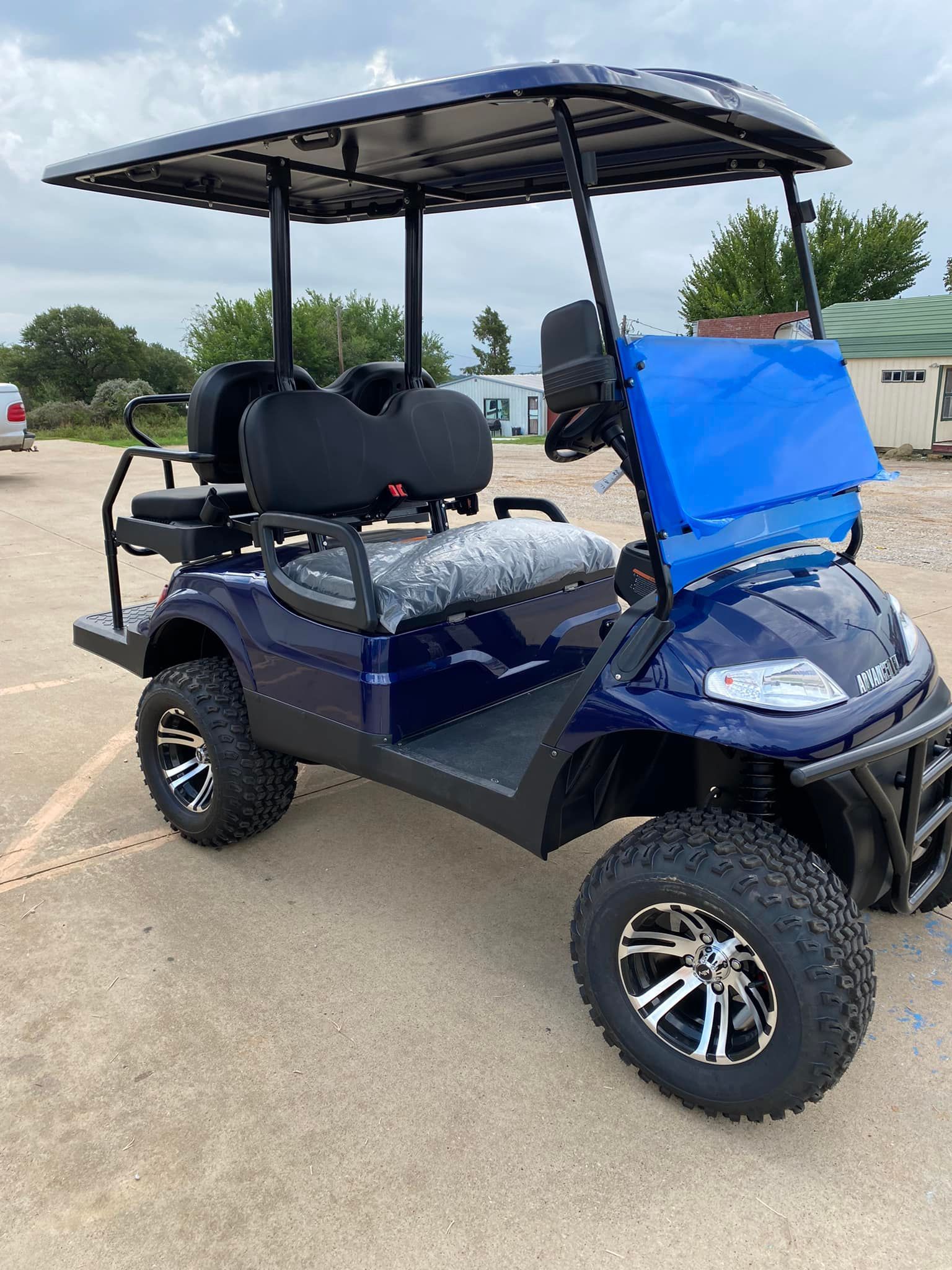 A blue golf cart is parked in a parking lot.