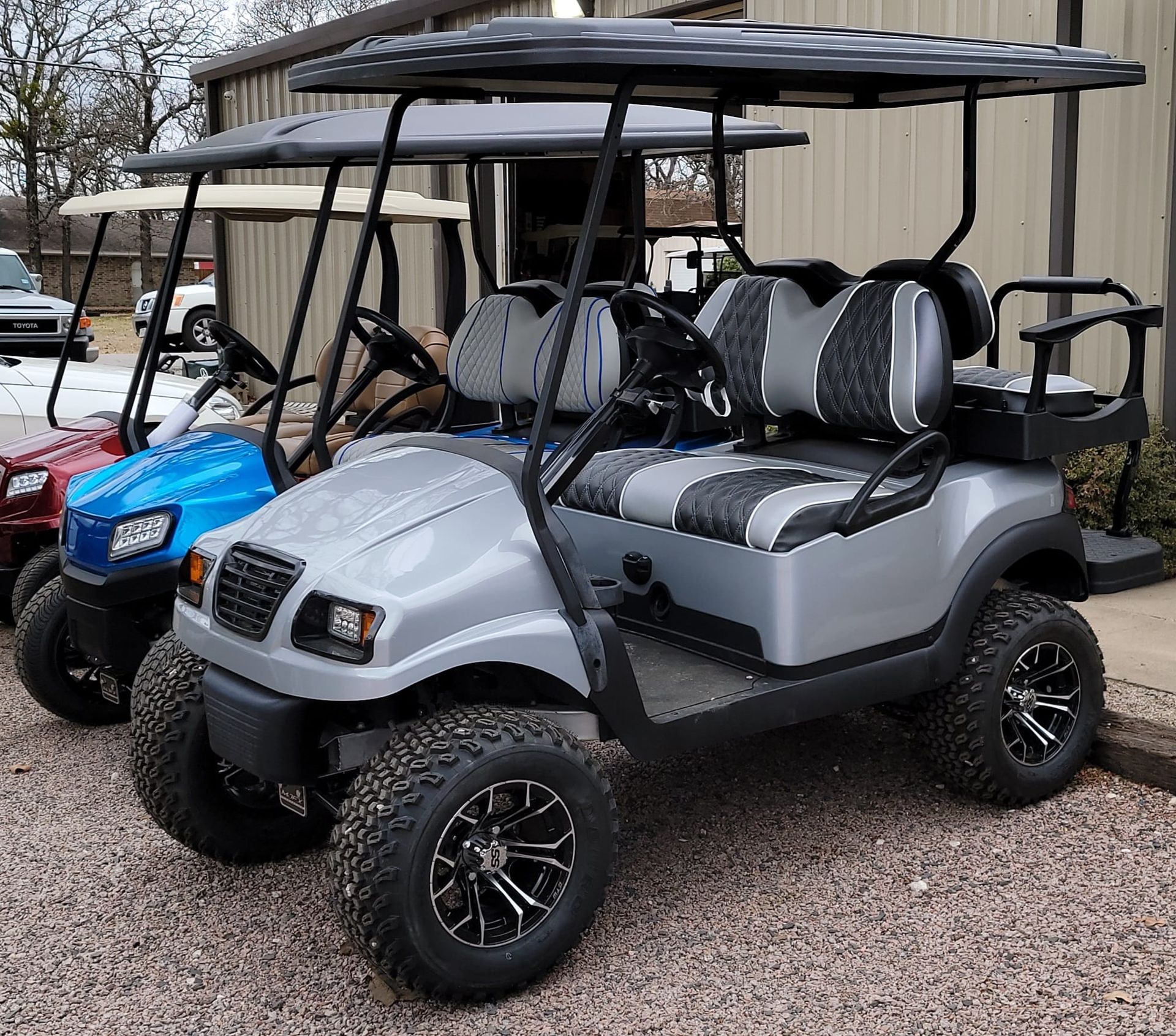 A row of golf carts are parked in front of a building.
