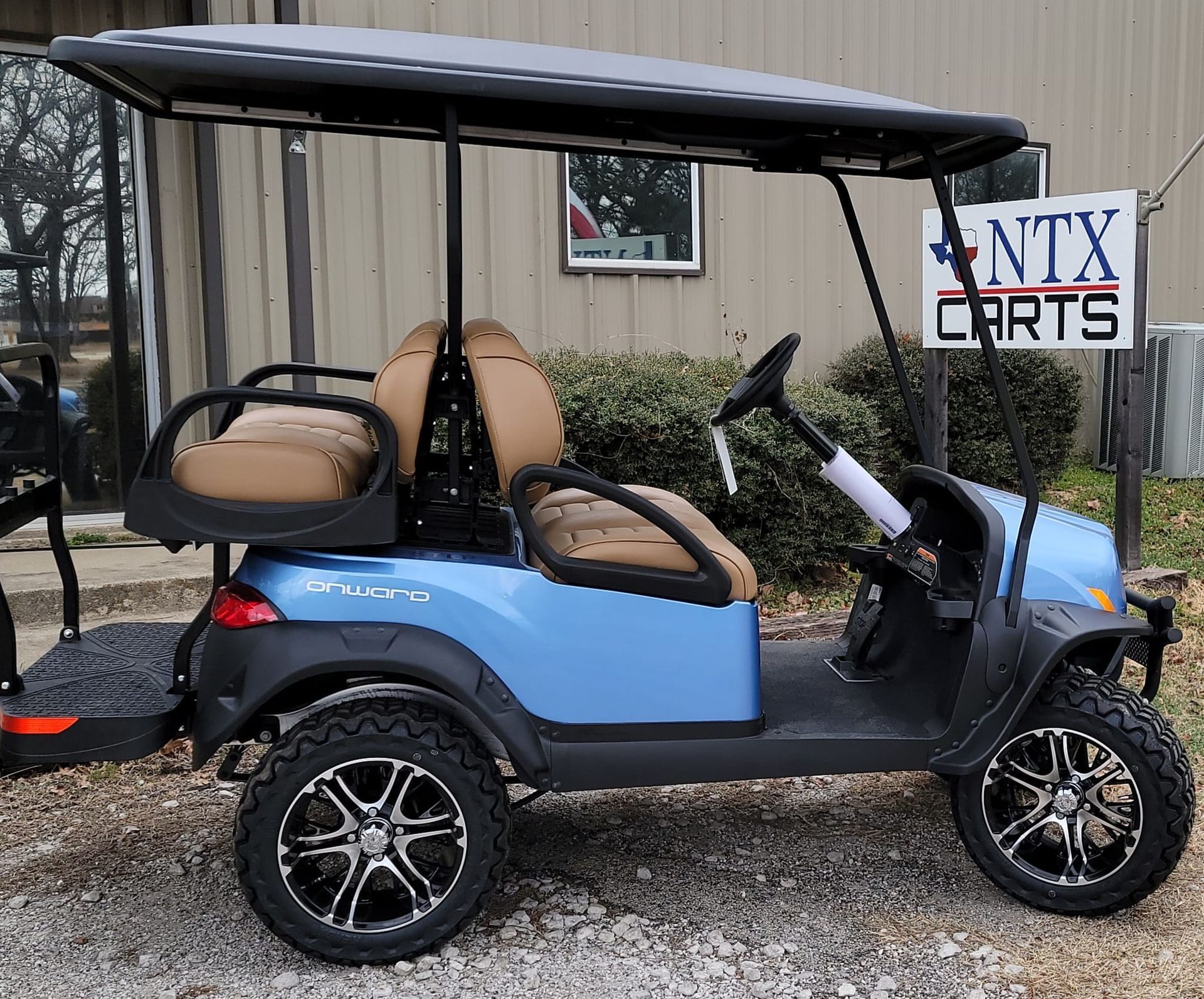 A blue golf cart is parked in front of a sign that says ntx carts