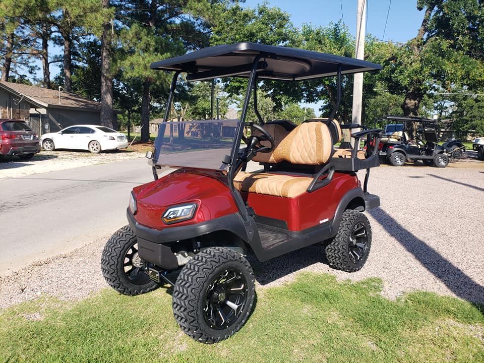 A red golf cart is parked on the side of the road.
