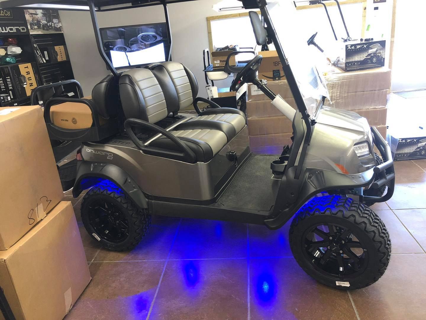 A golf cart with blue lights on the wheels is parked in a room.