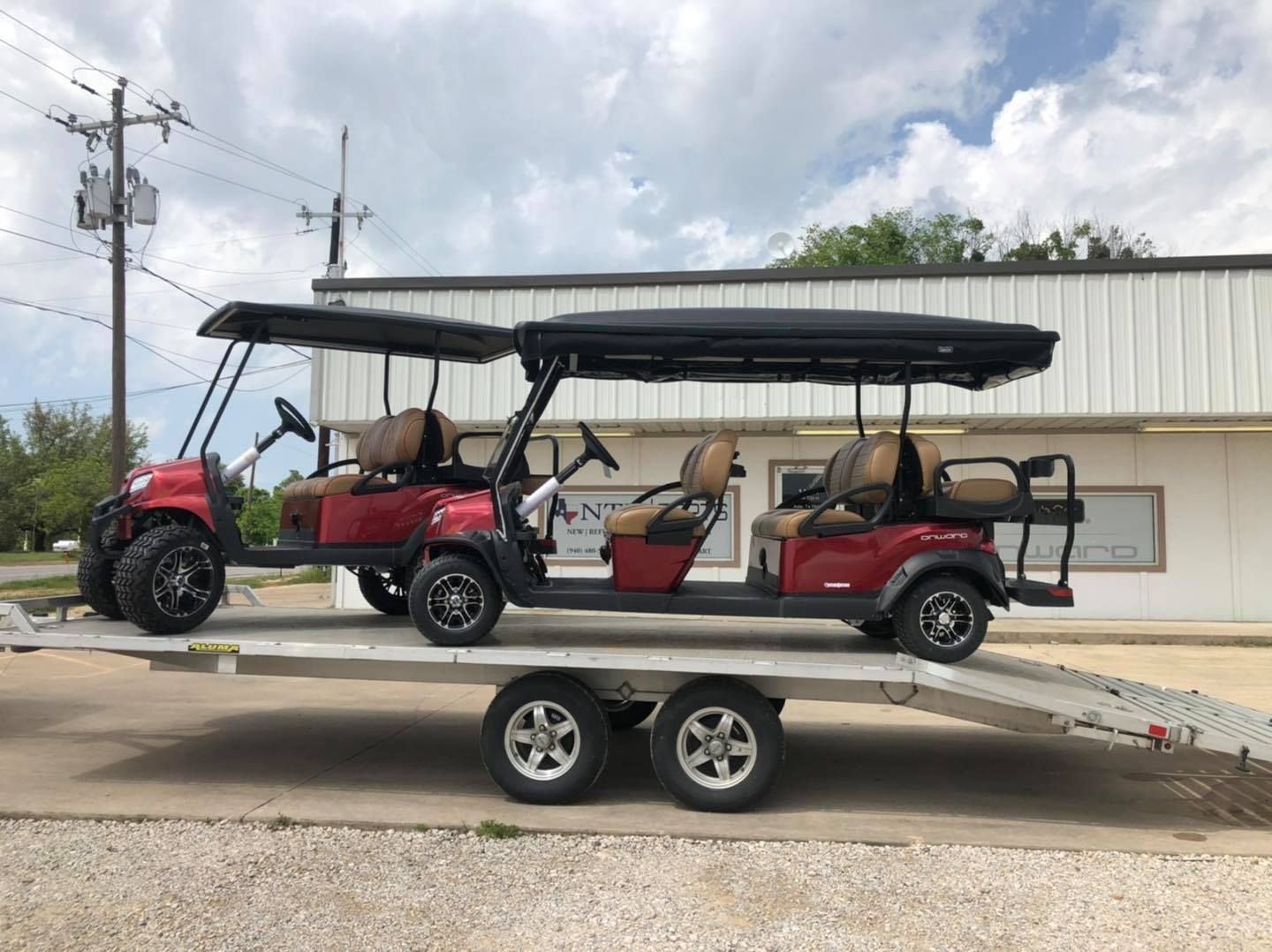 Two golf carts are sitting on a trailer in front of a building.