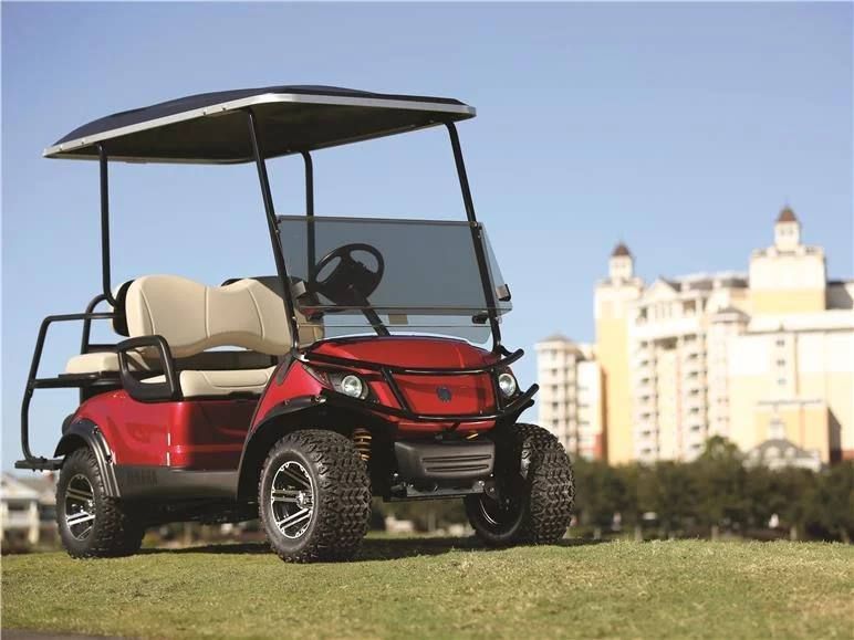 A red golf cart is parked on a lush green field