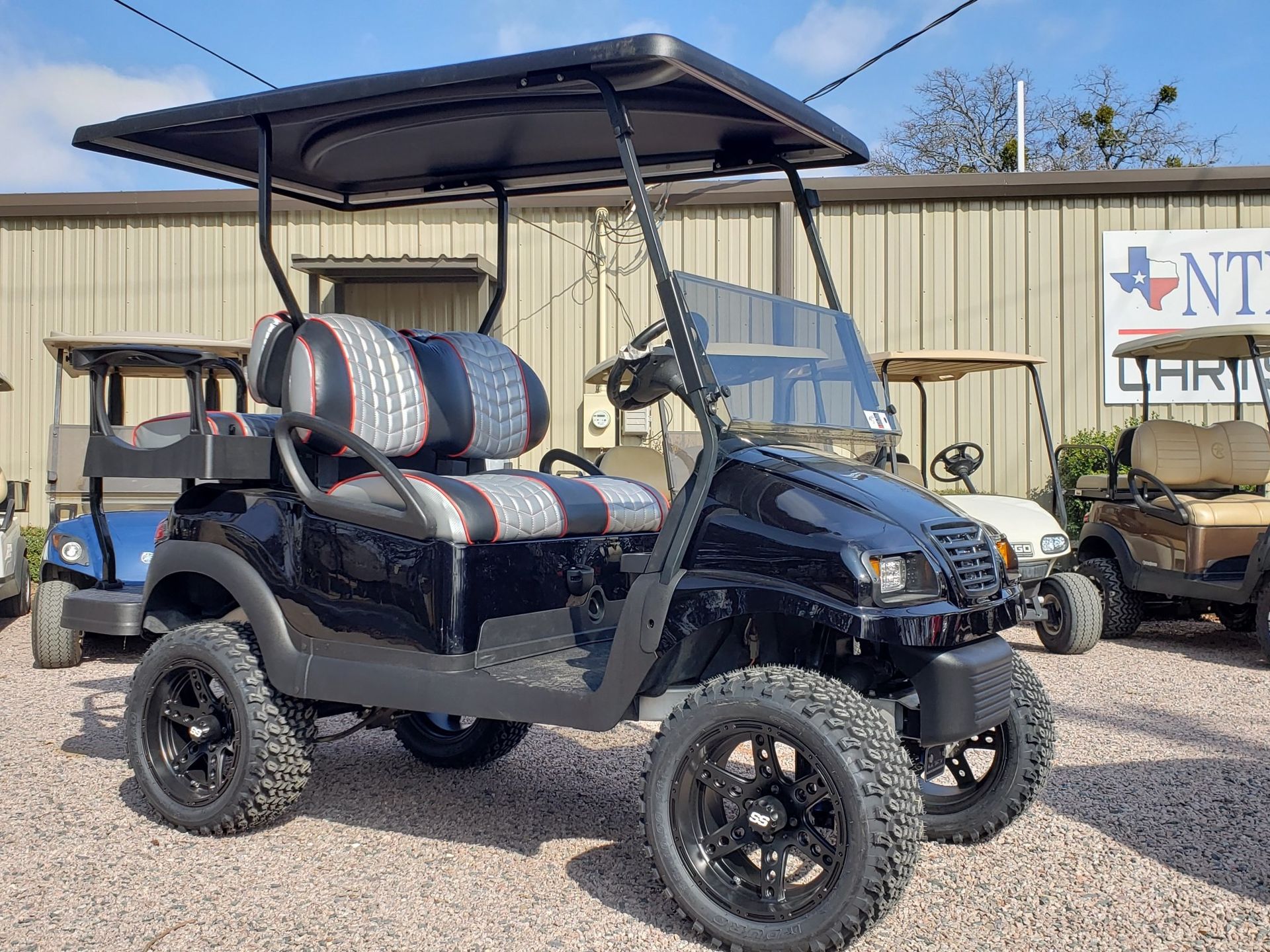 A black golf cart is parked in front of a building.