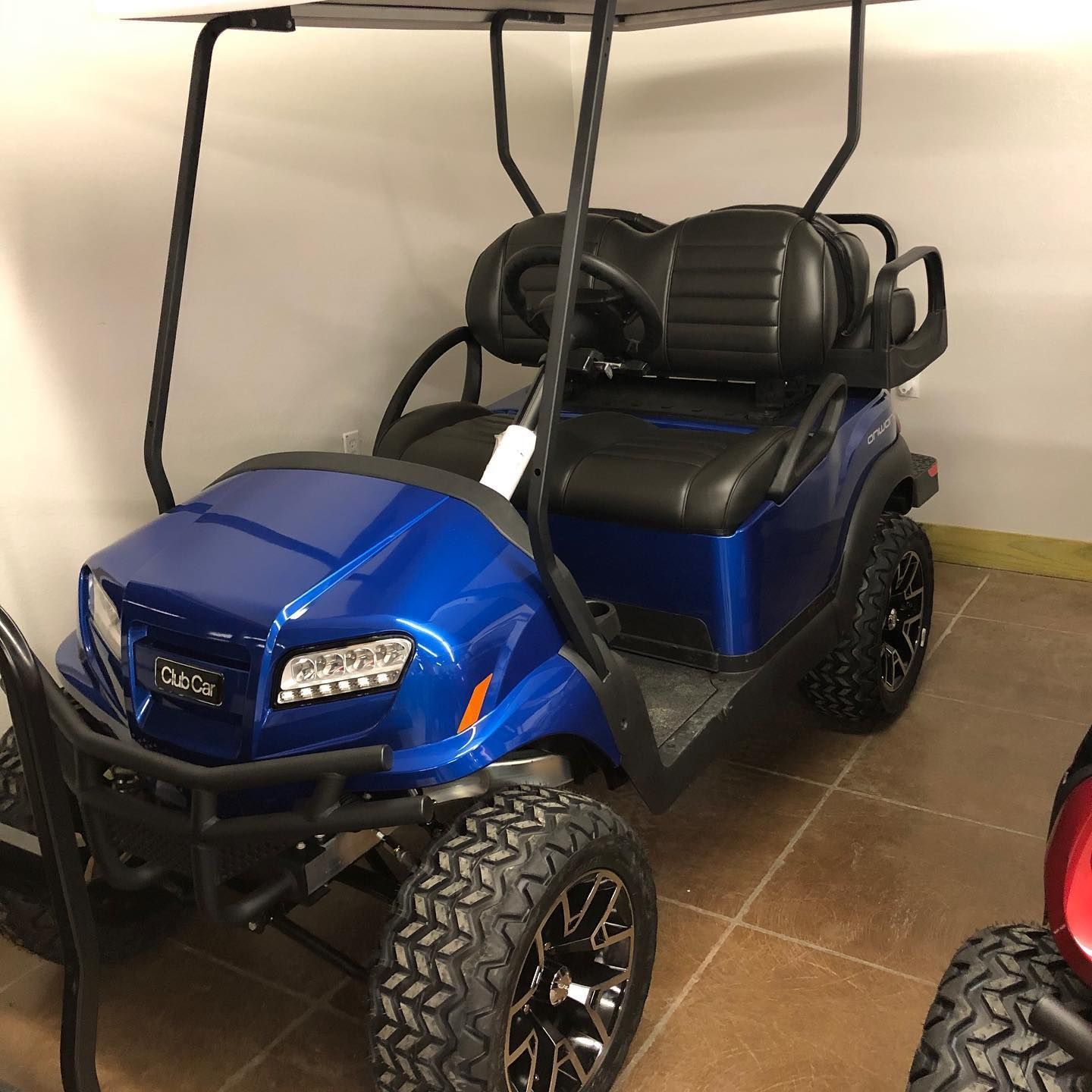 A blue golf cart with black seats is parked in a garage.