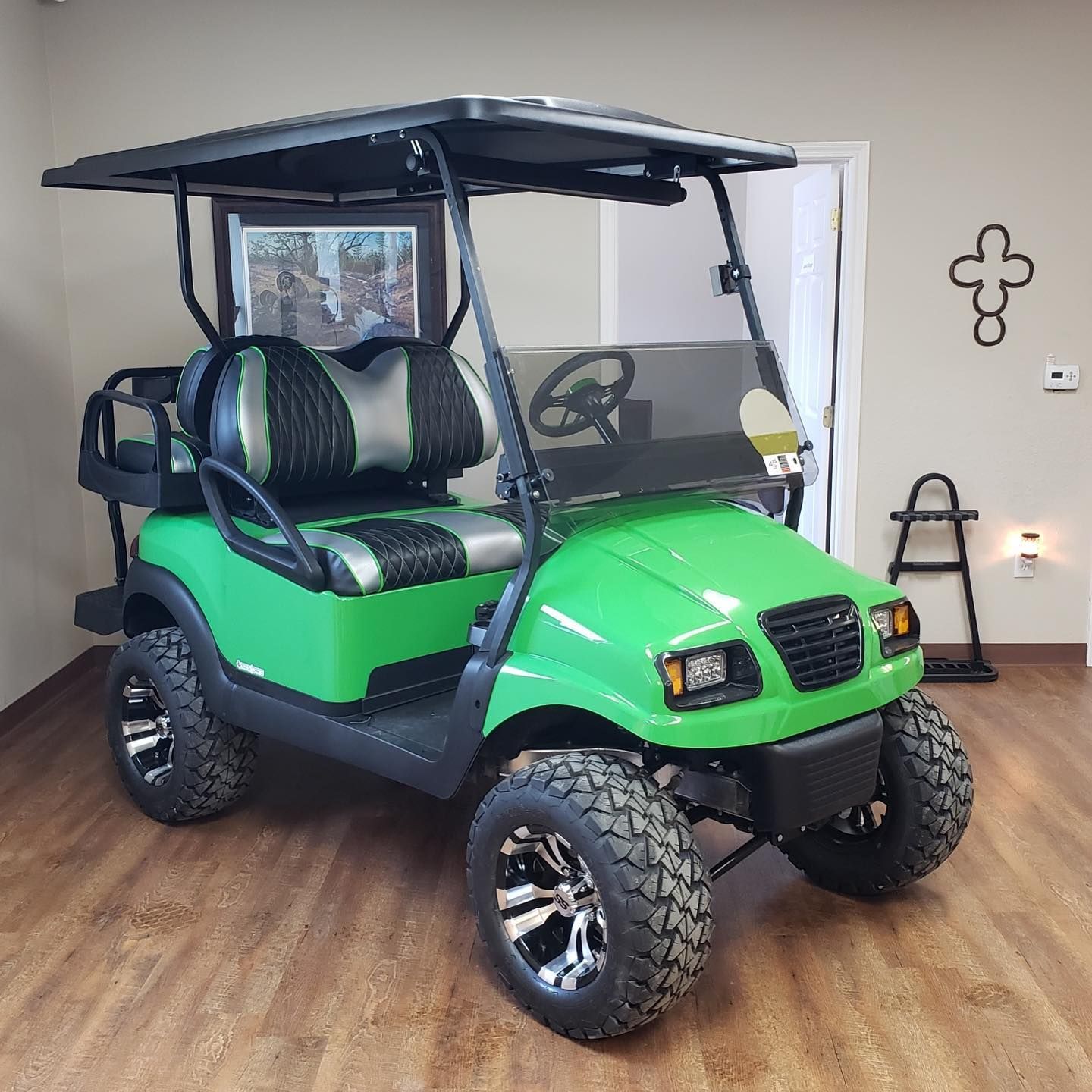A green golf cart is parked in a room.