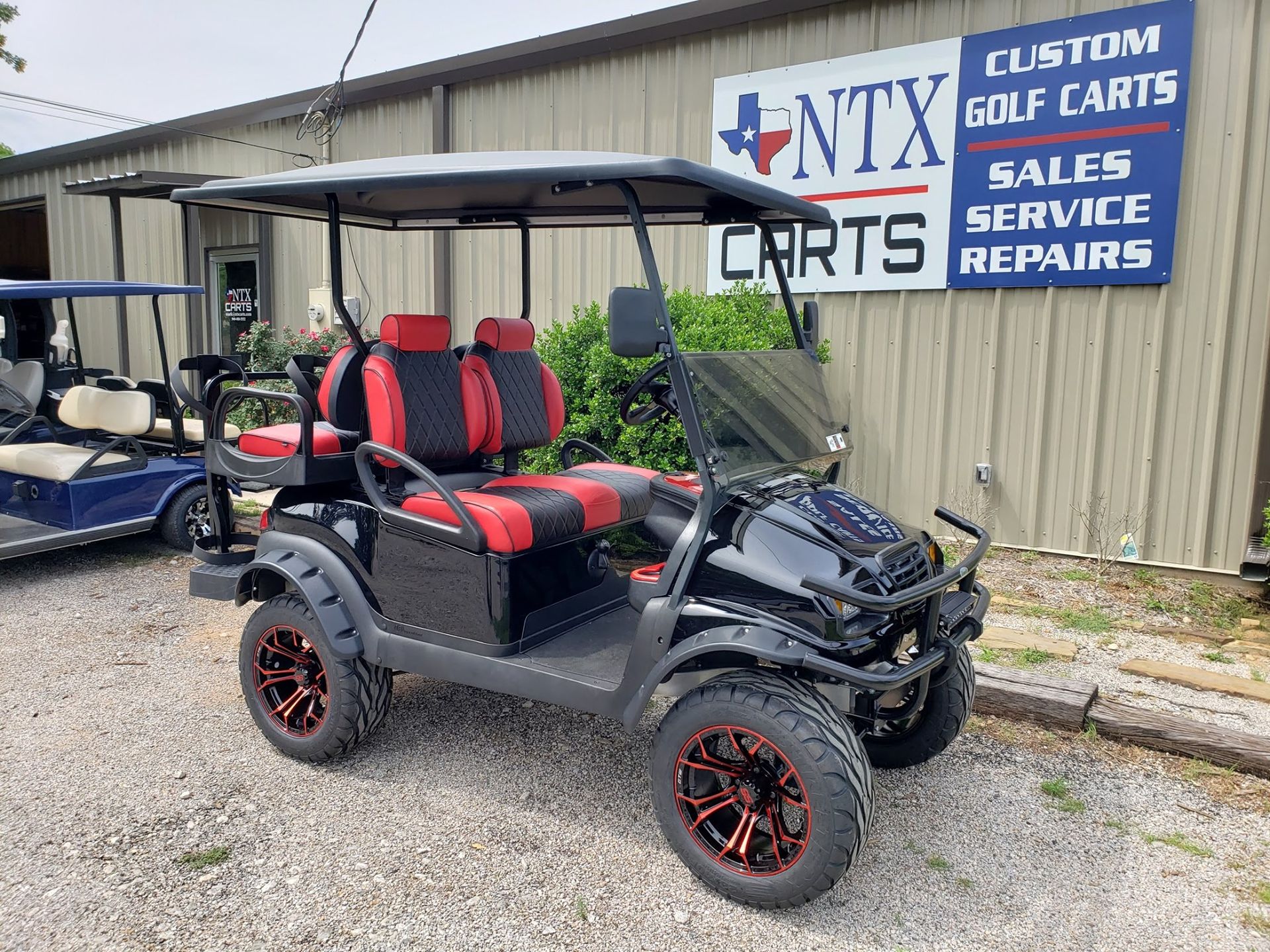 A black and red golf cart is parked in front of a building.