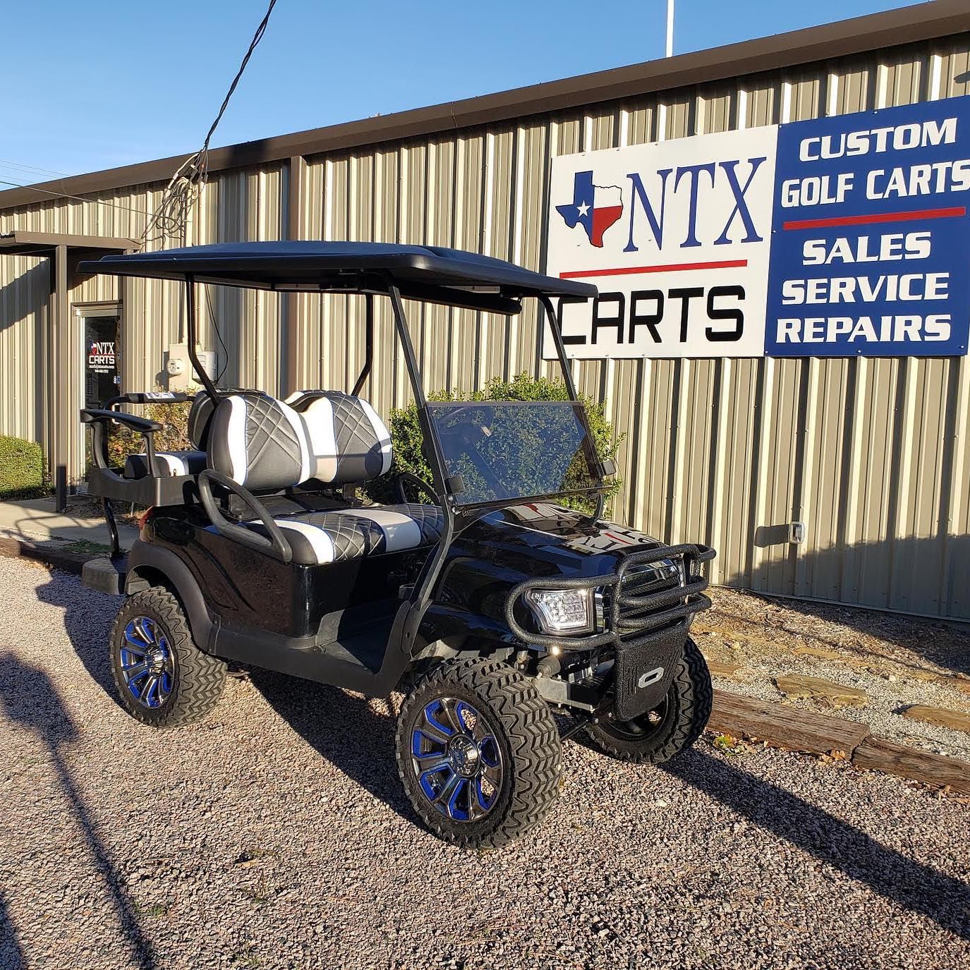 A golf cart is parked in front of a sign for ntx golf carts