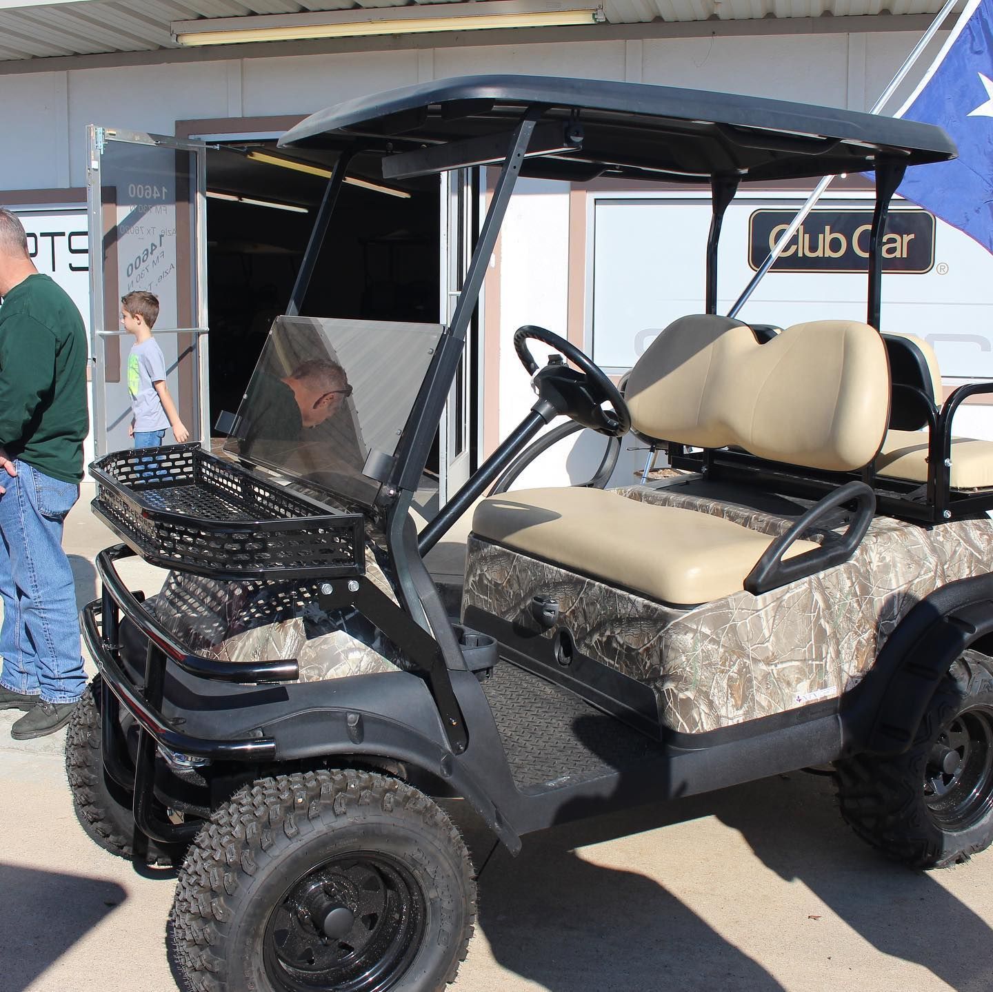 A golf cart is parked in front of a building that says club car