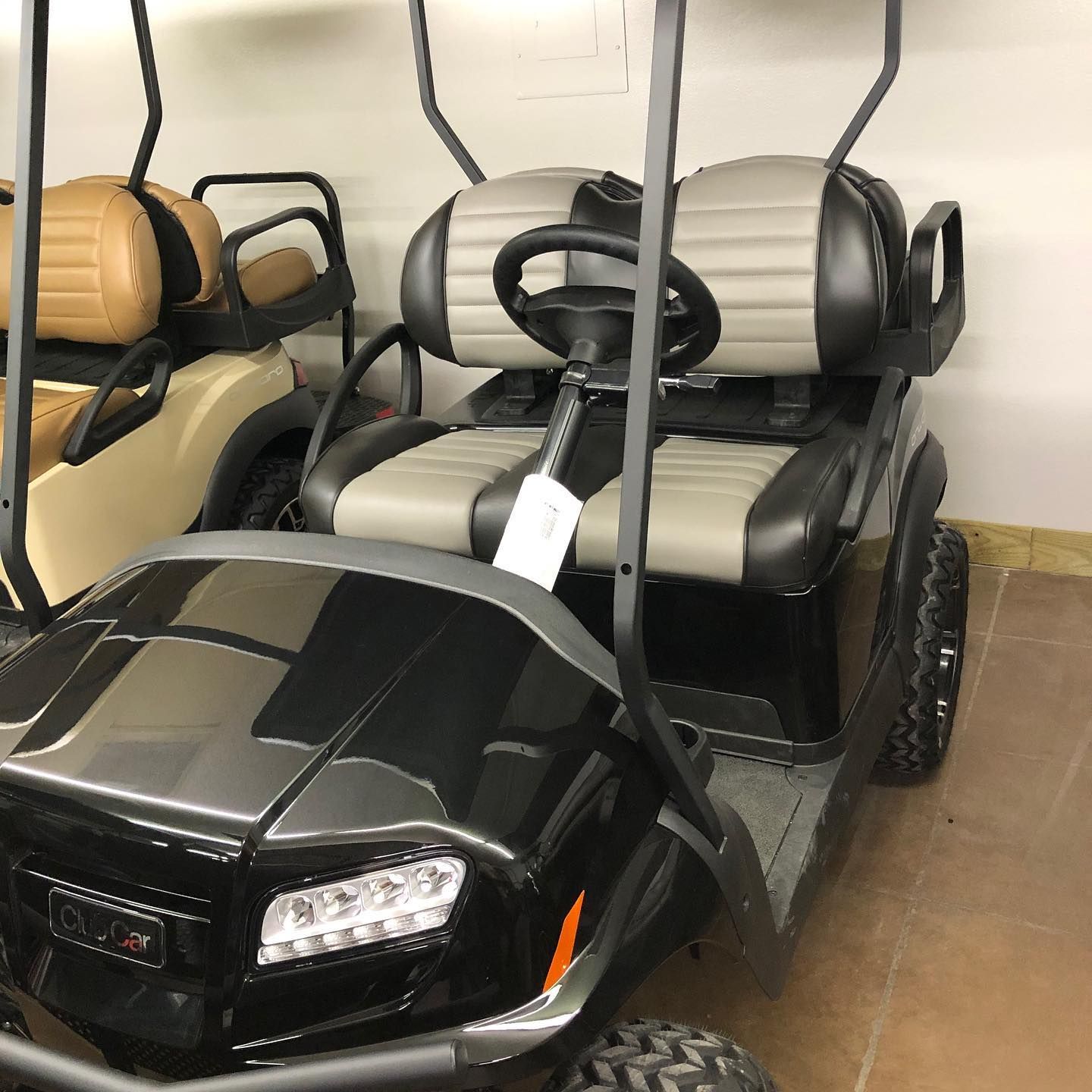 A black golf cart with gray seats is parked in a garage.
