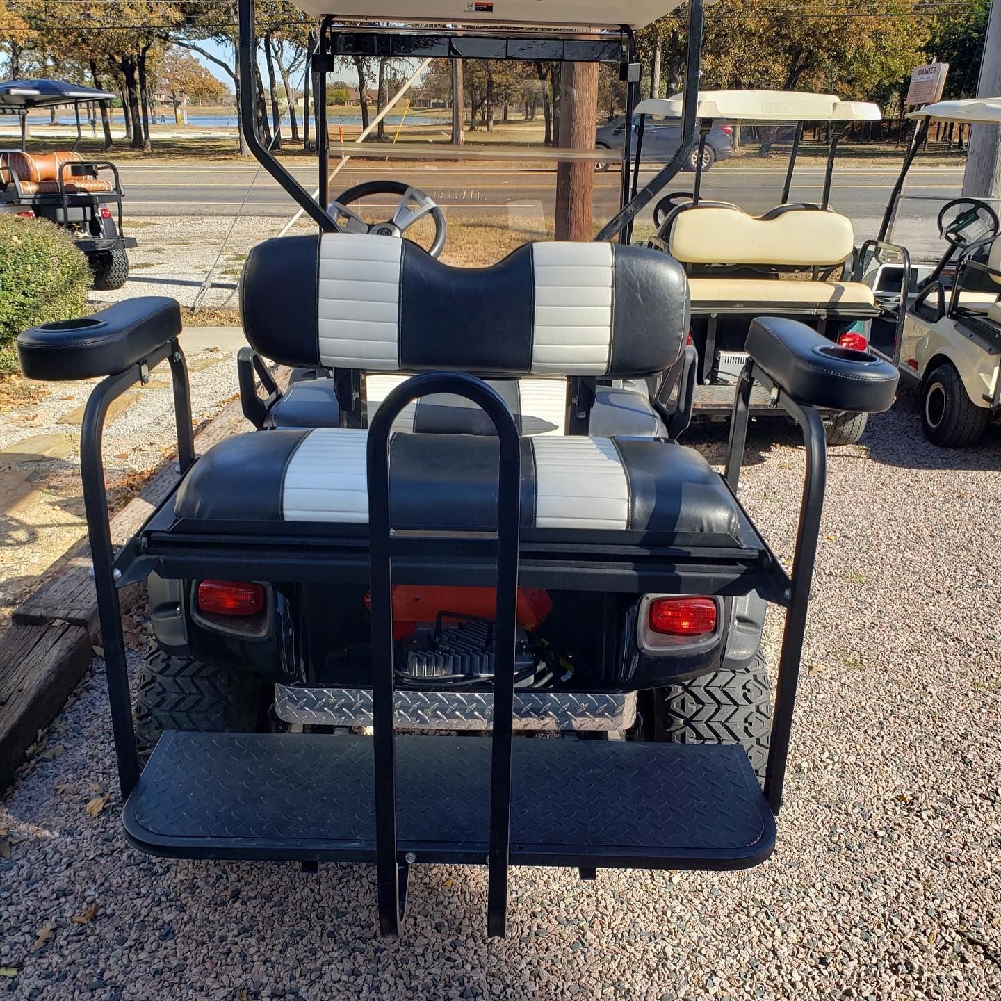 A black and white golf cart is parked on gravel.