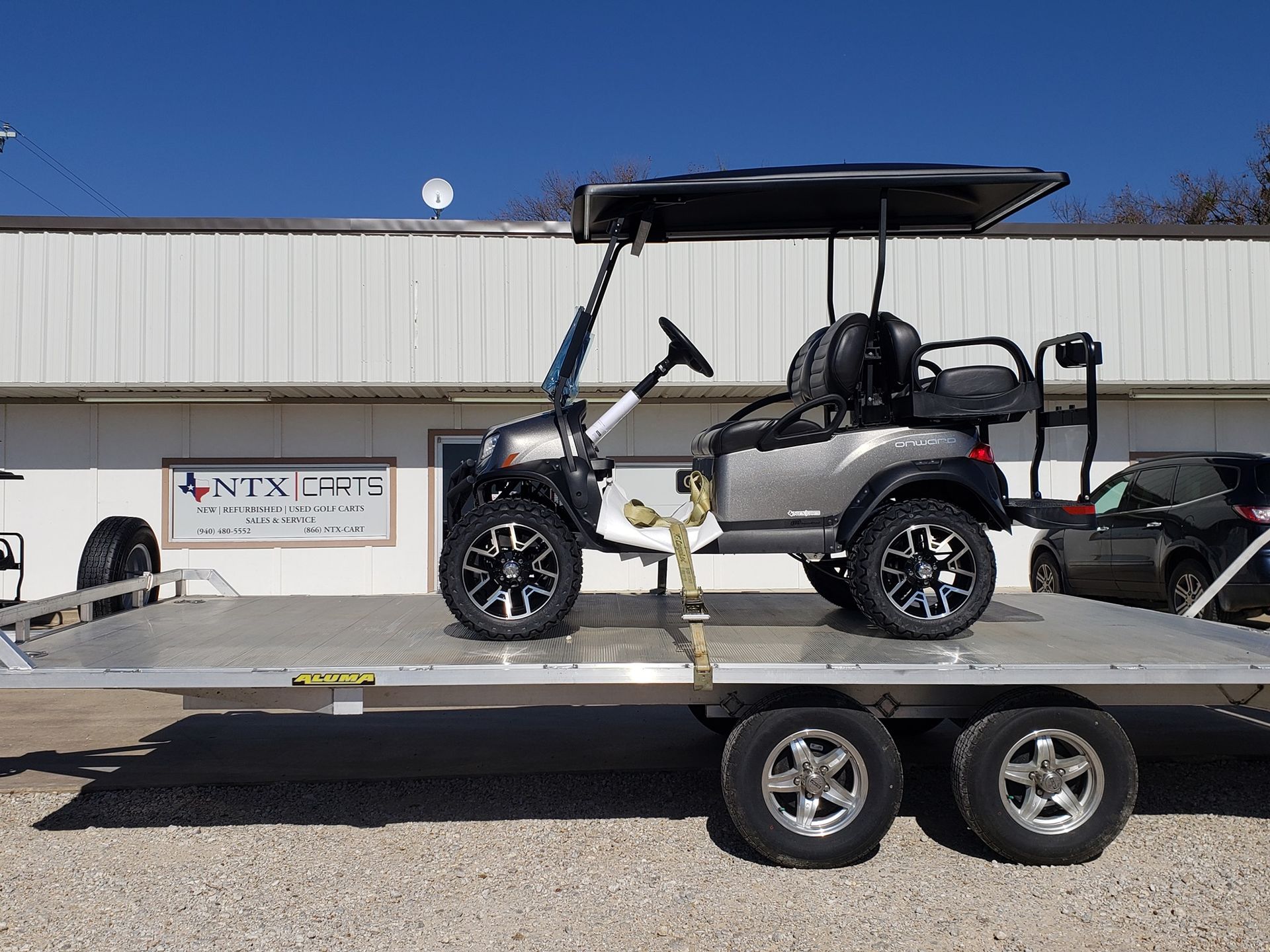 A golf cart is sitting on top of a trailer.