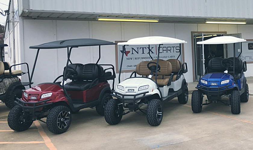 A group of golf carts are parked in front of a building.