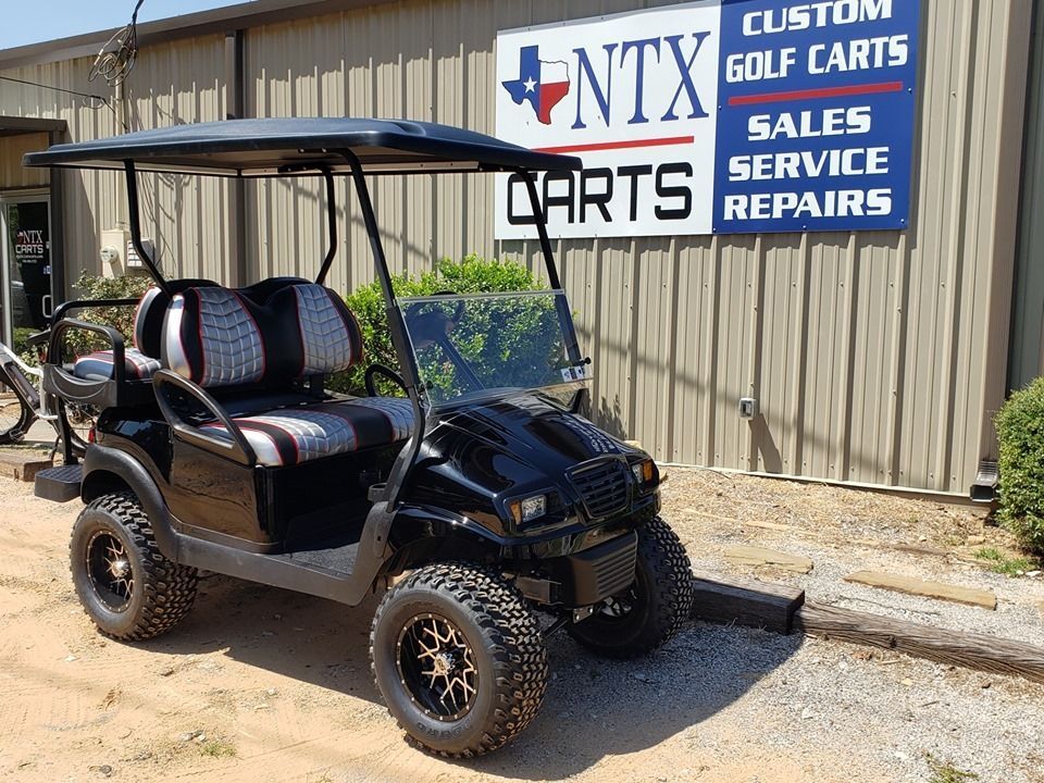 A black golf cart is parked in front of a building.