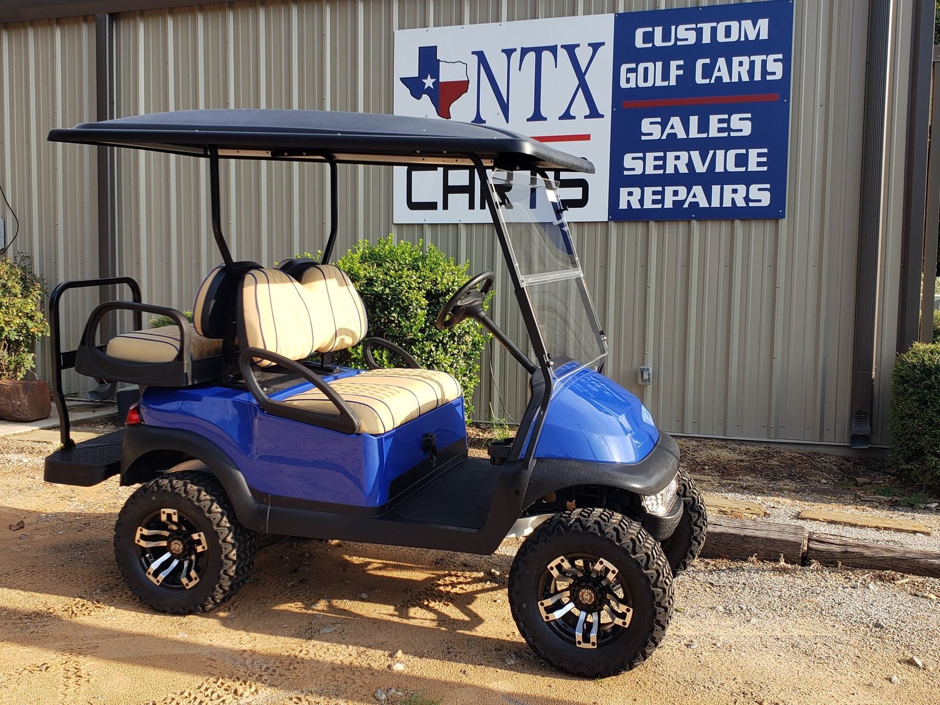 A blue golf cart is parked in front of a building.