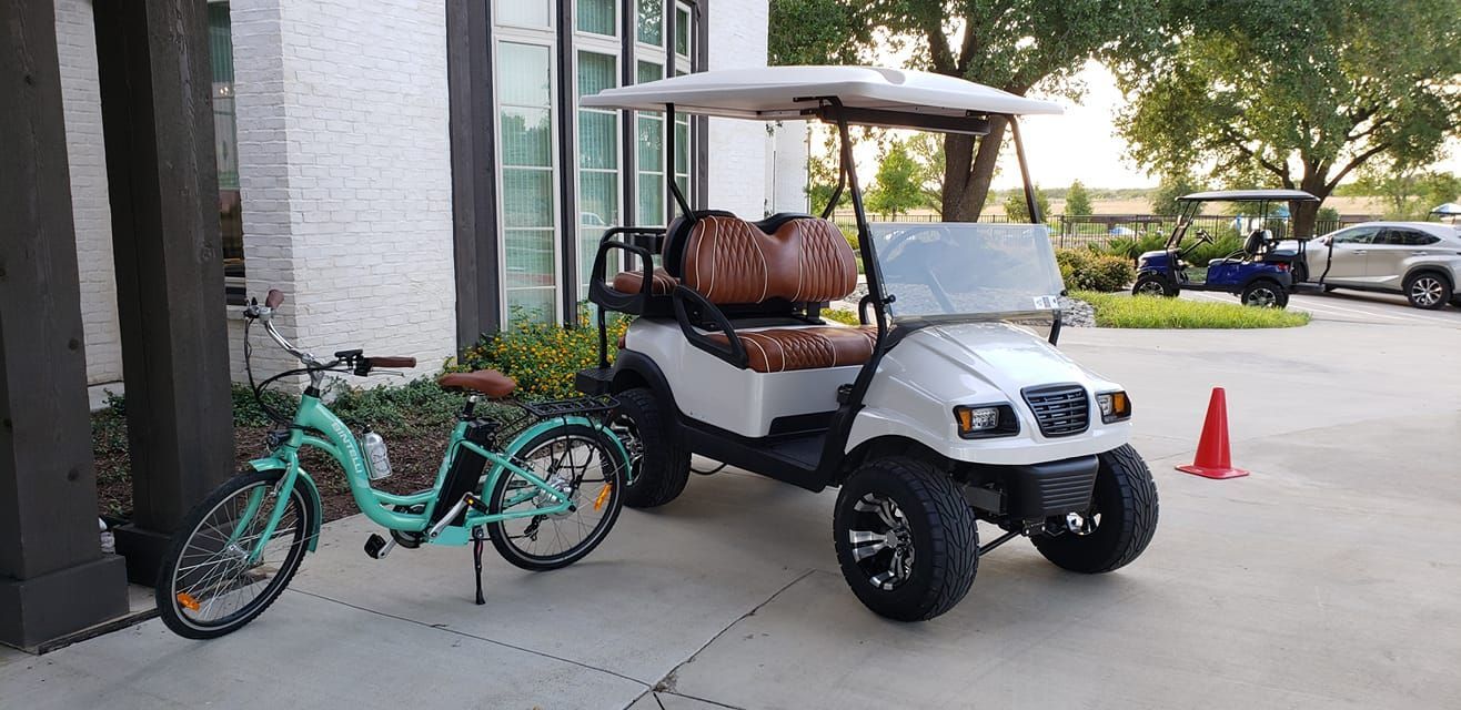 A golf cart and a bicycle are parked in front of a house.