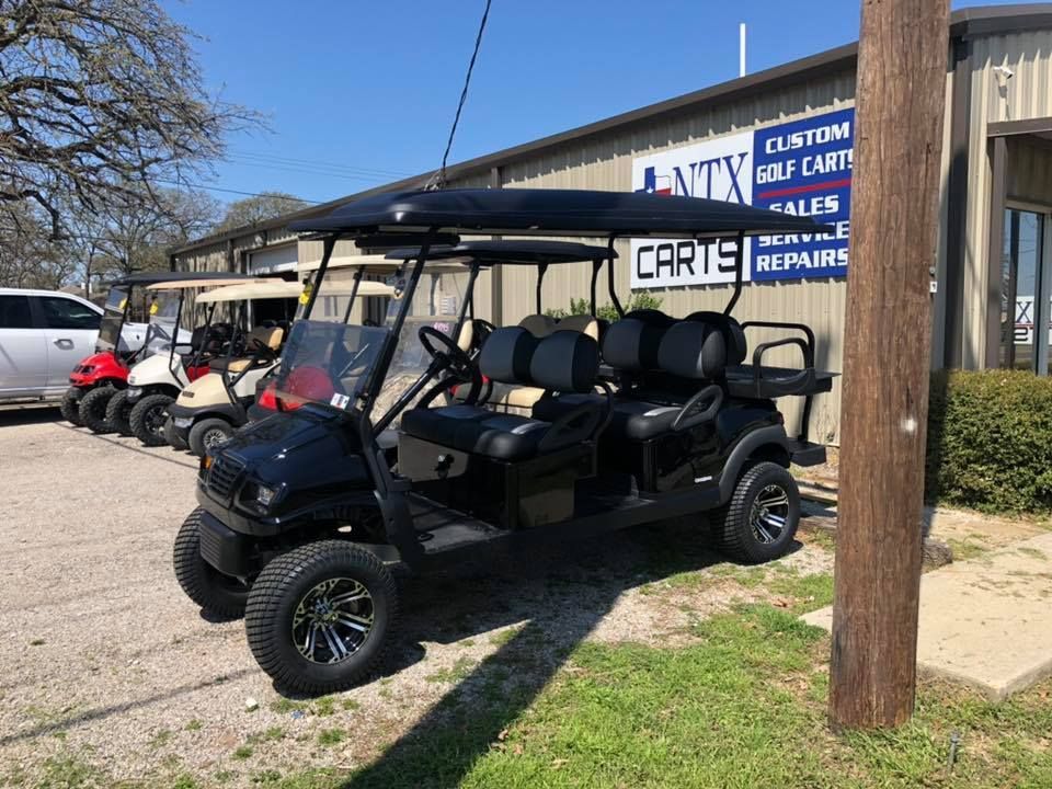 A black golf cart is parked in front of a building.