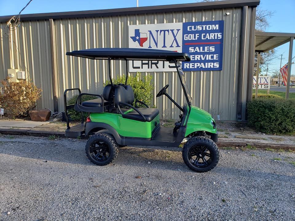 A green golf cart is parked in front of a building.
