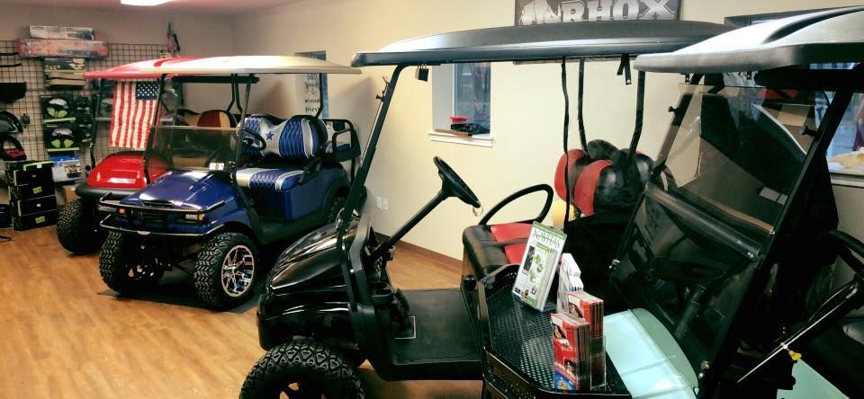 A bunch of golf carts are parked in a room.