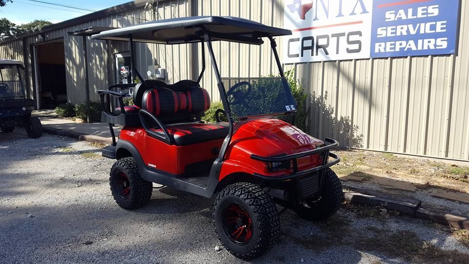 A red golf cart is parked in front of a building.