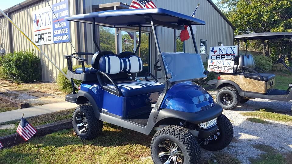 A blue golf cart is parked in front of a building.