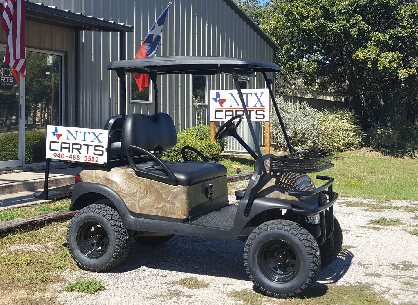 A golf cart is parked in front of a building that says ntx carts