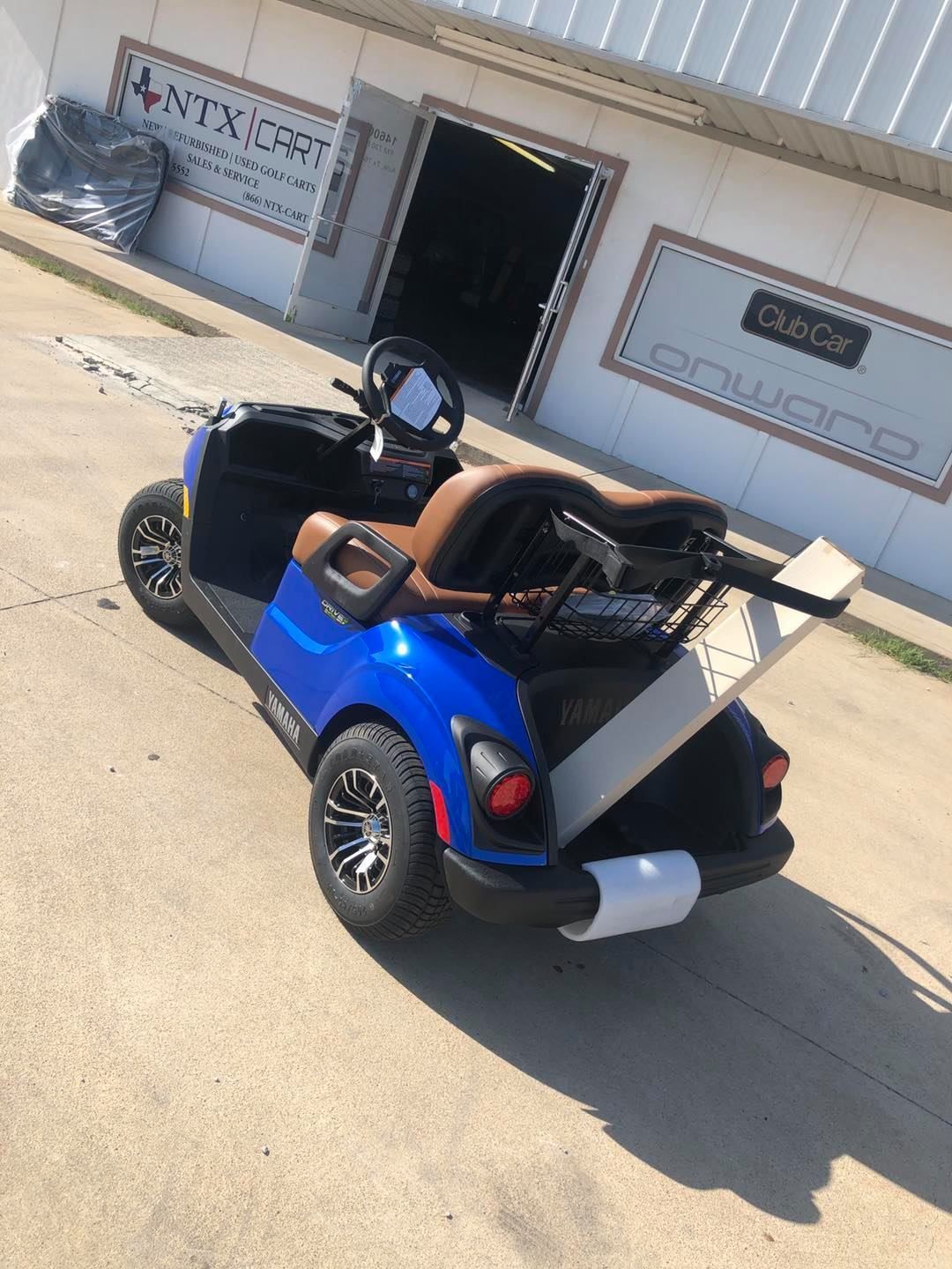 A blue golf cart is parked in front of a building.