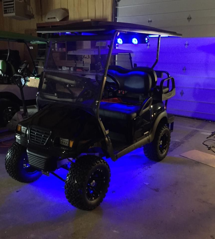 A golf cart is parked in a garage with blue lights.
