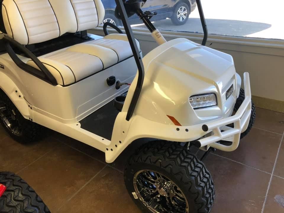 A white golf cart is parked in a garage.