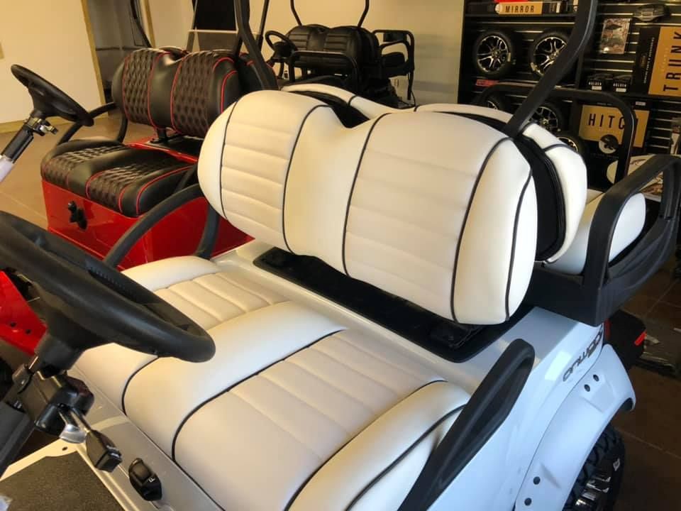A white golf cart with black stripes on the seats