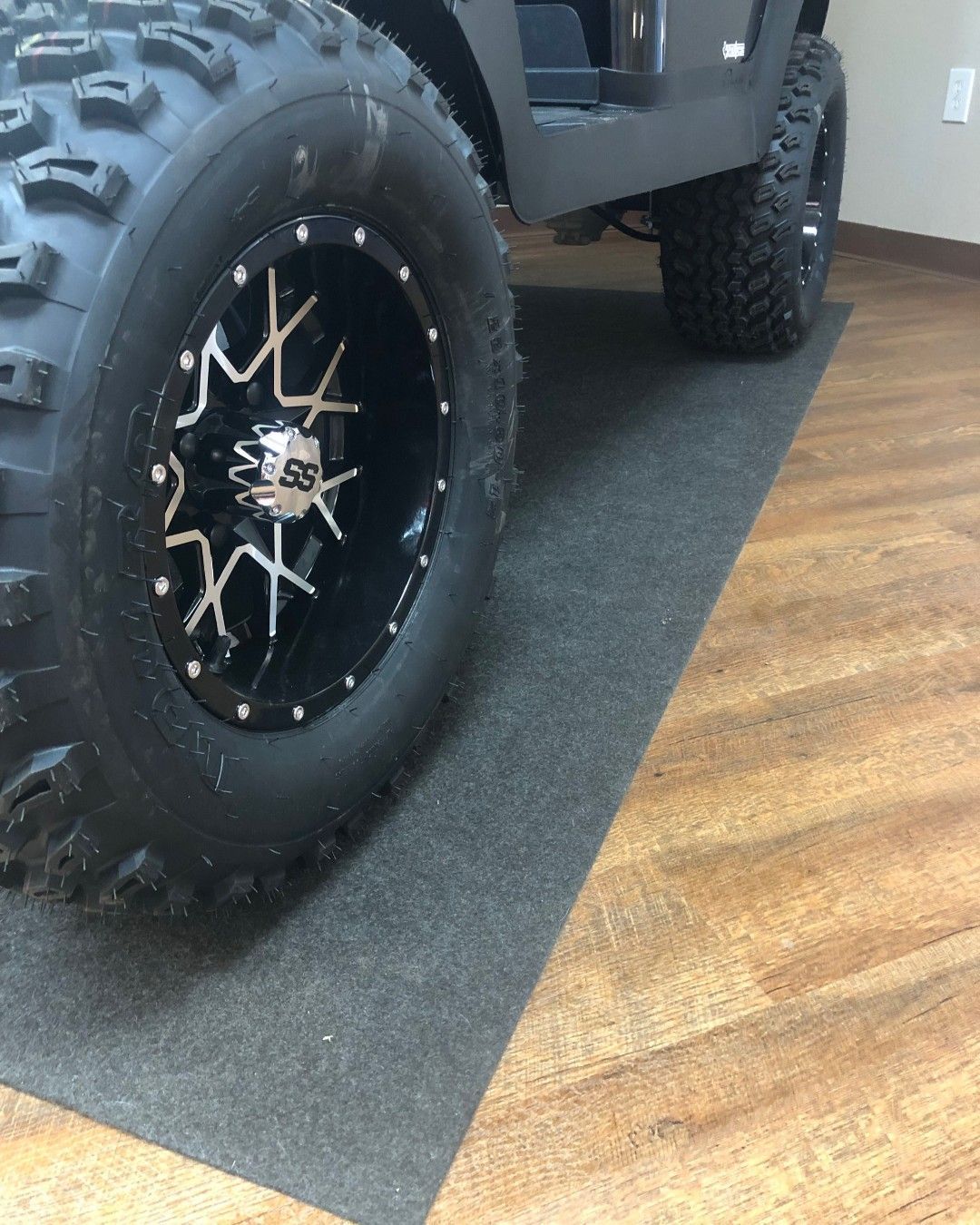 A golf cart is parked on a mat on the floor.