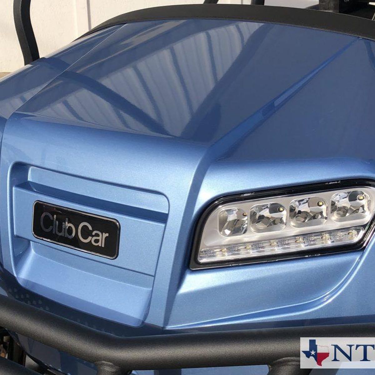 A blue club car is parked in front of a building