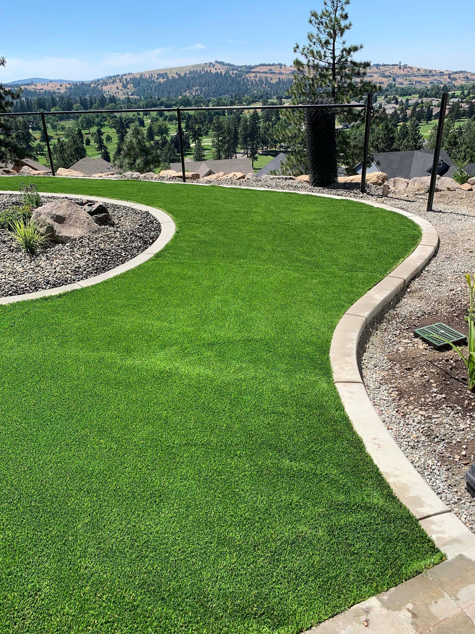 A lush green lawn with a stone walkway and a view of the mountains.
