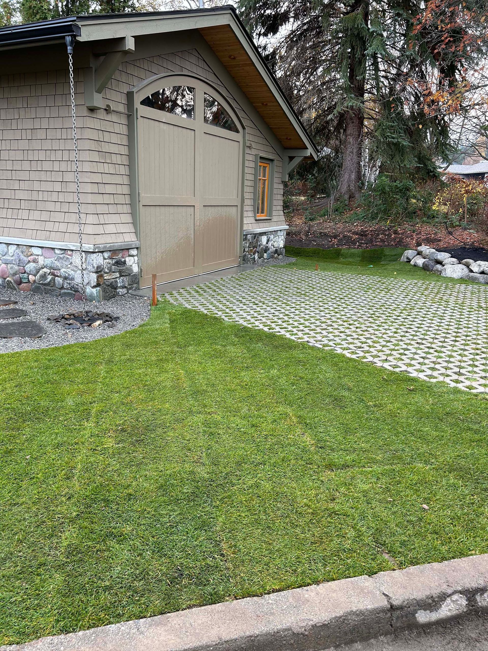A house with a large garage door and a lush green lawn in front of it.