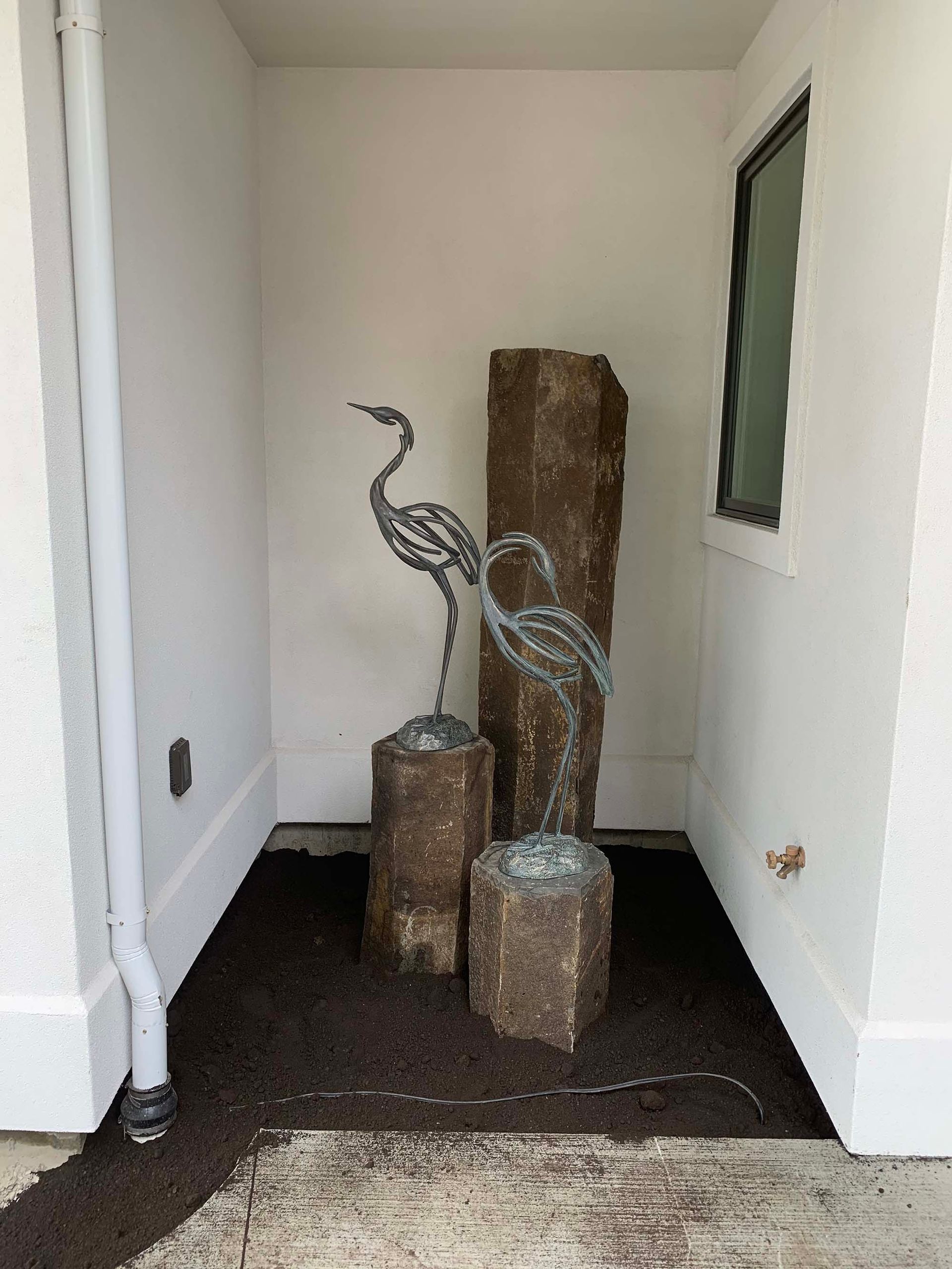 There is a fountain in the corner of the house.