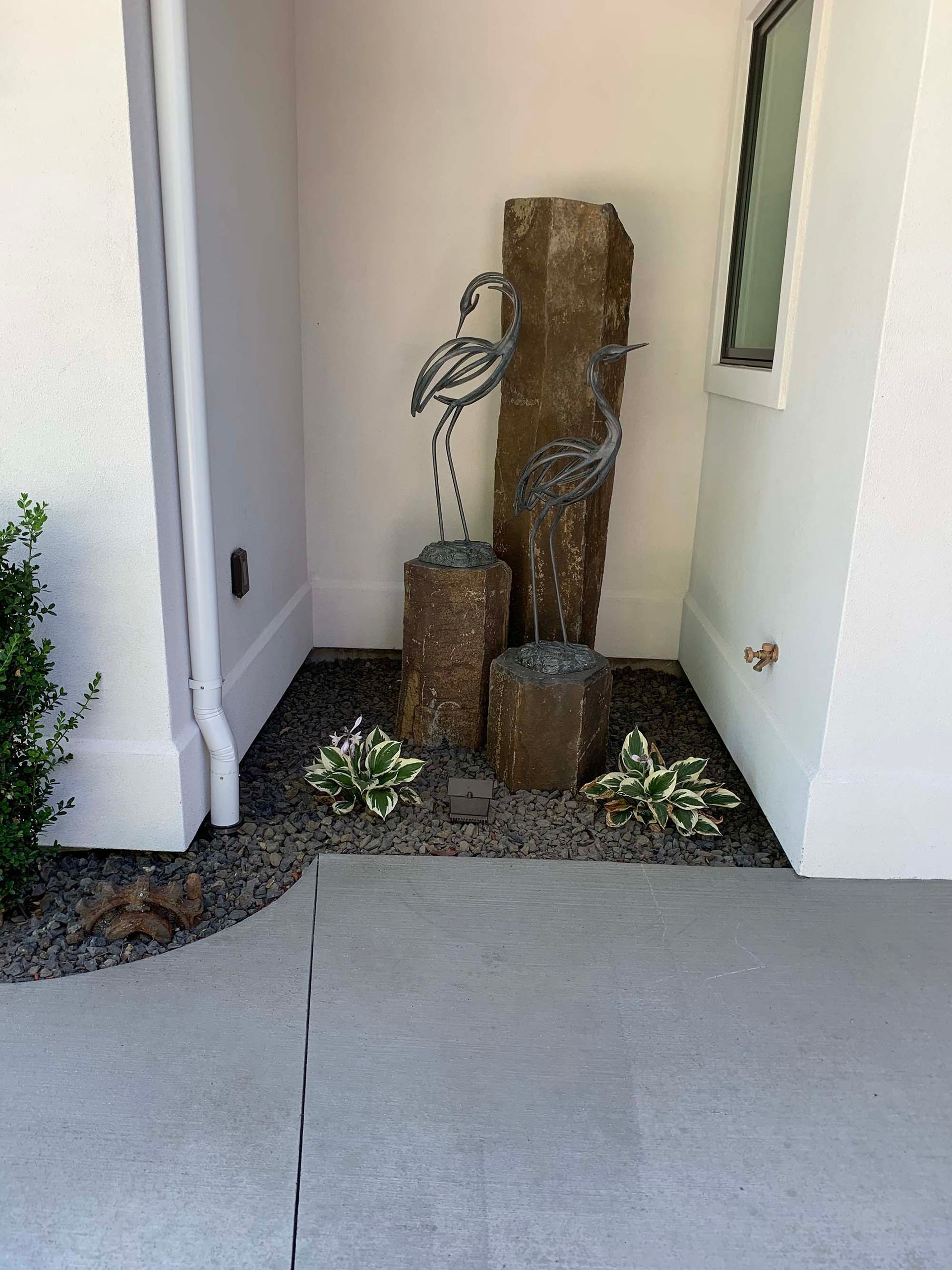 There is a fountain in the corner of the house.