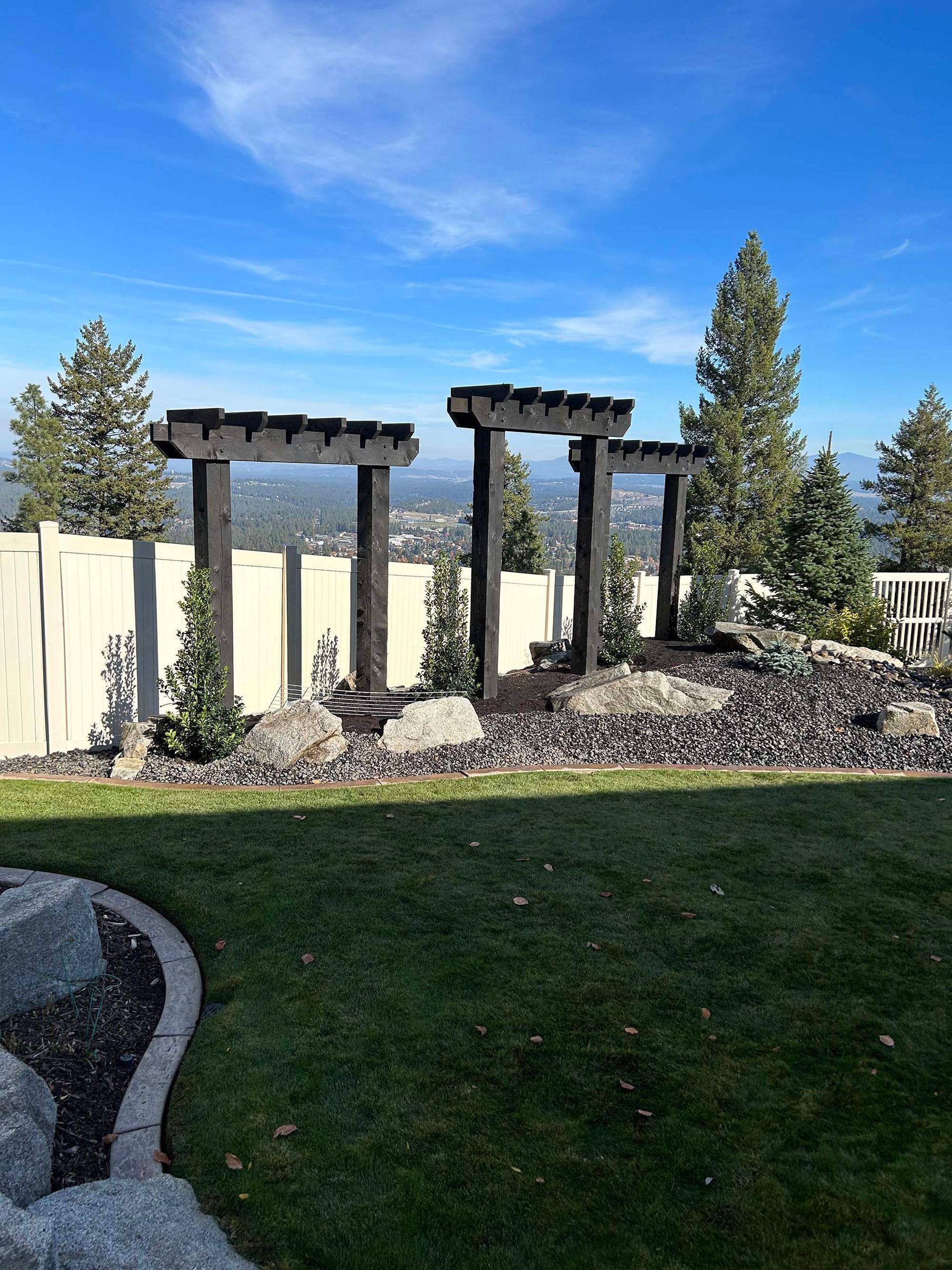 A backyard with a pergola and a white fence