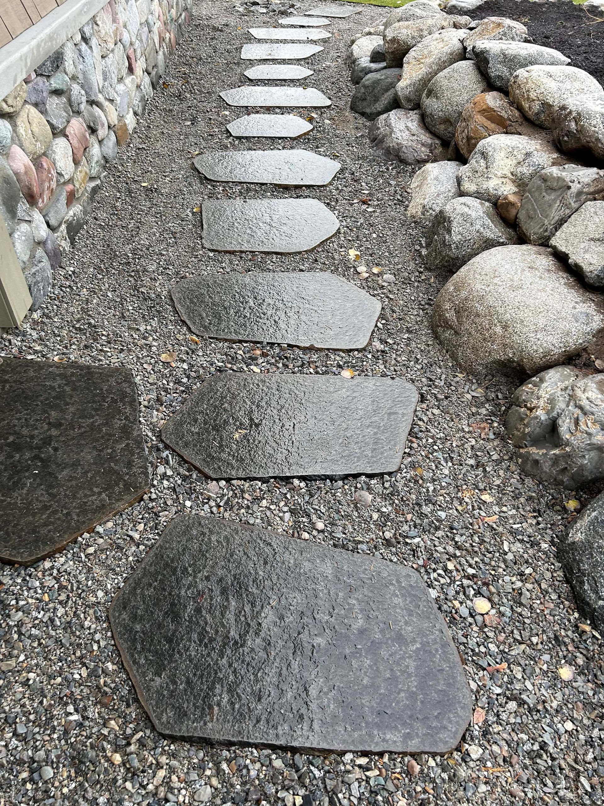 A row of stepping stones lined up on a gravel path.