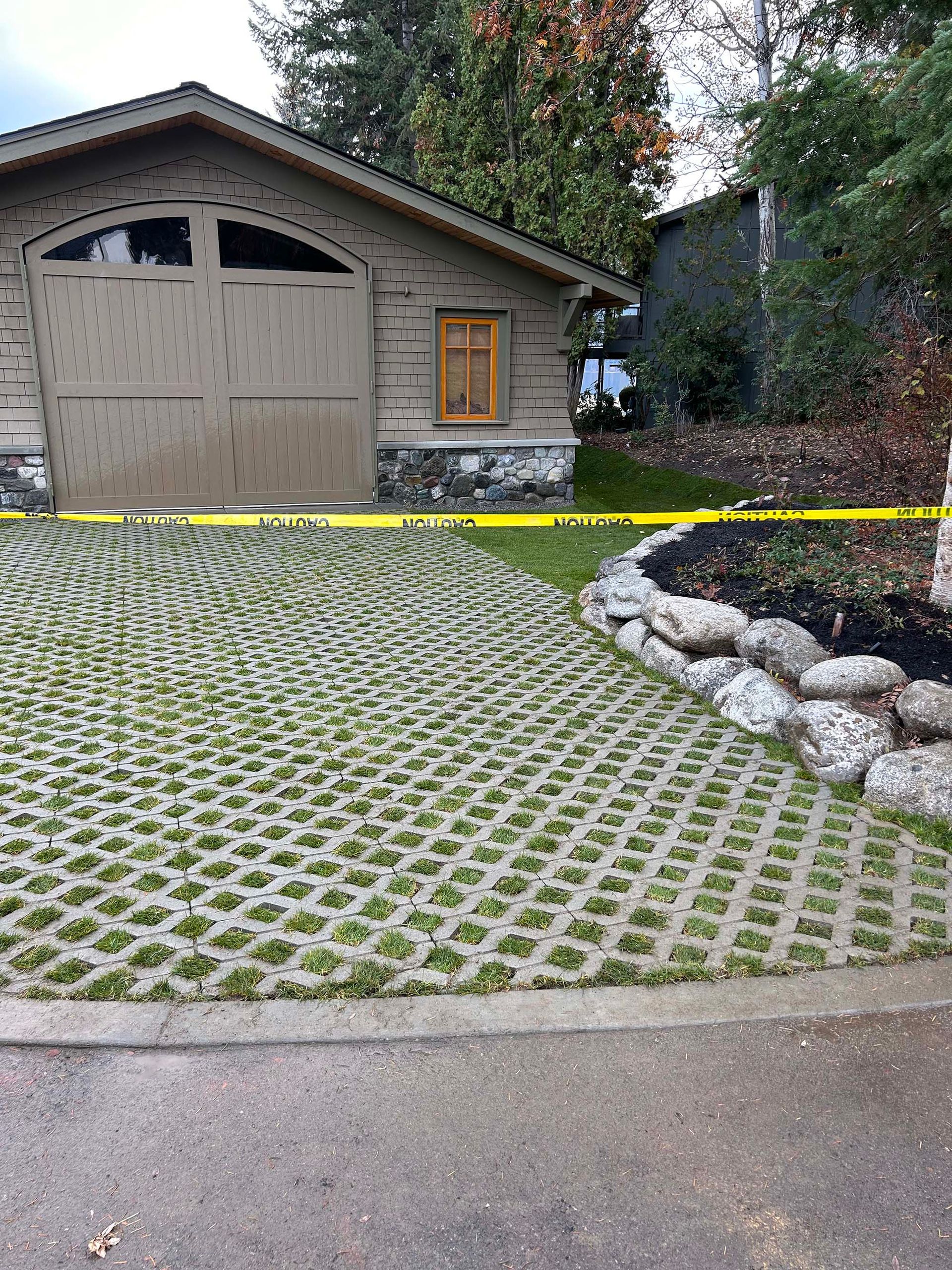 A house with a garage and a grassy driveway in front of it.